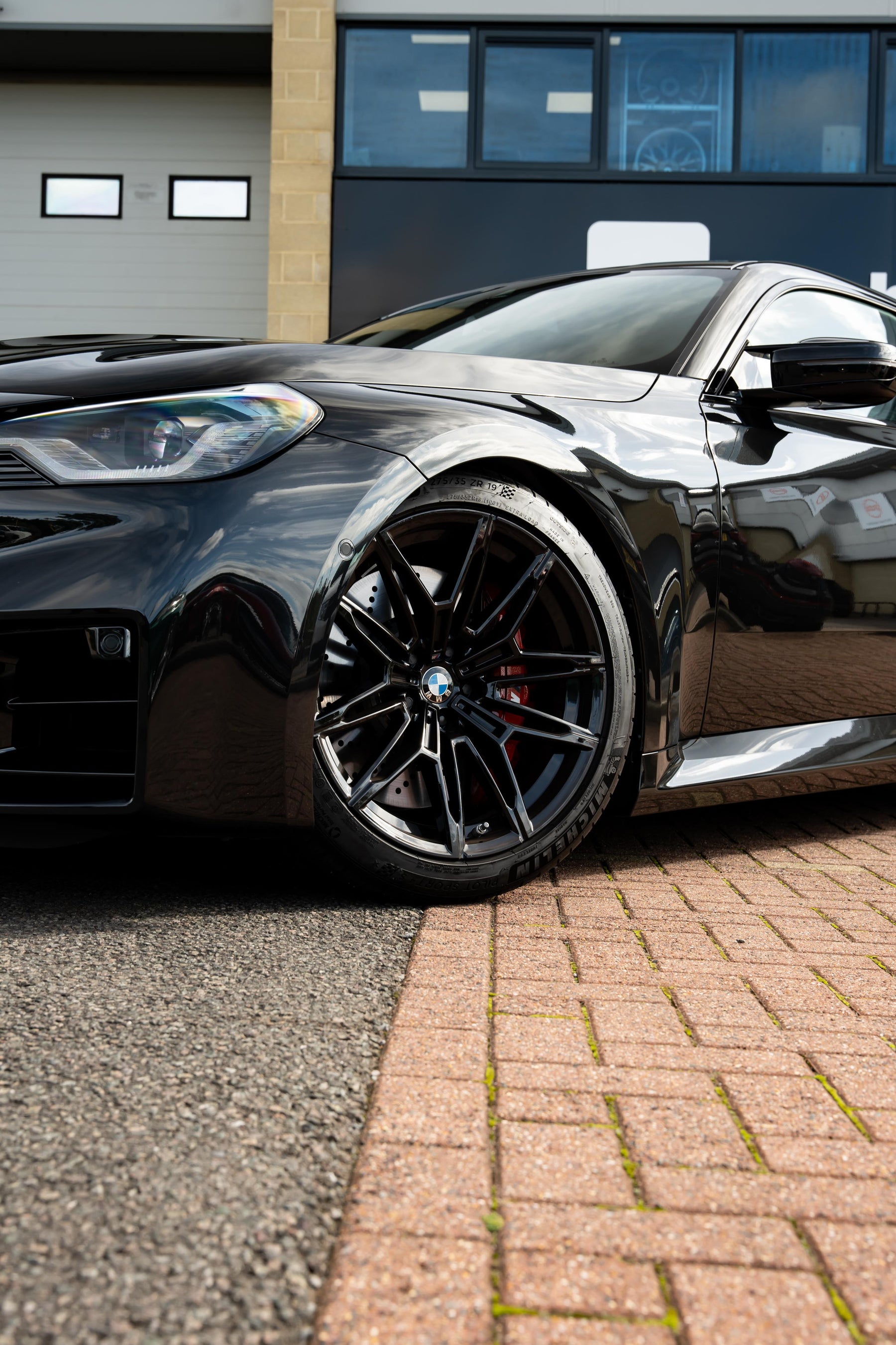 Black BMW car parked on a driveway in front of a building