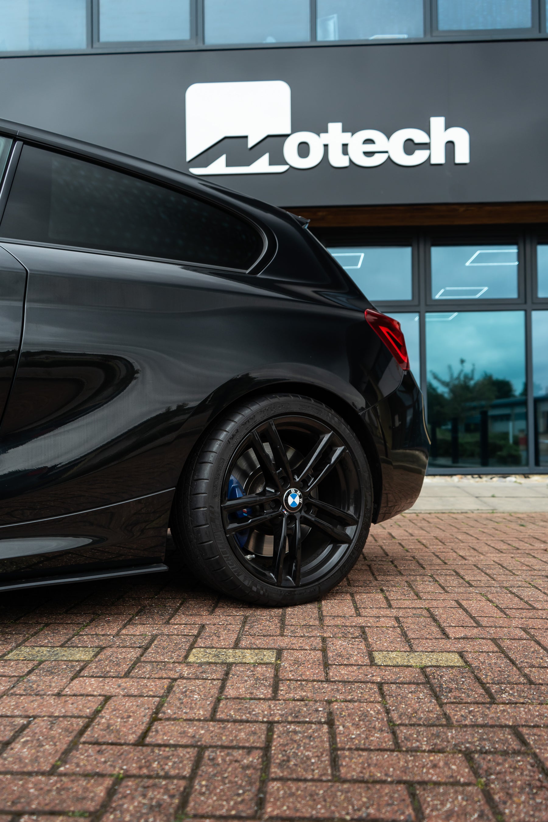 The back of a black BMW outside the Motech building.