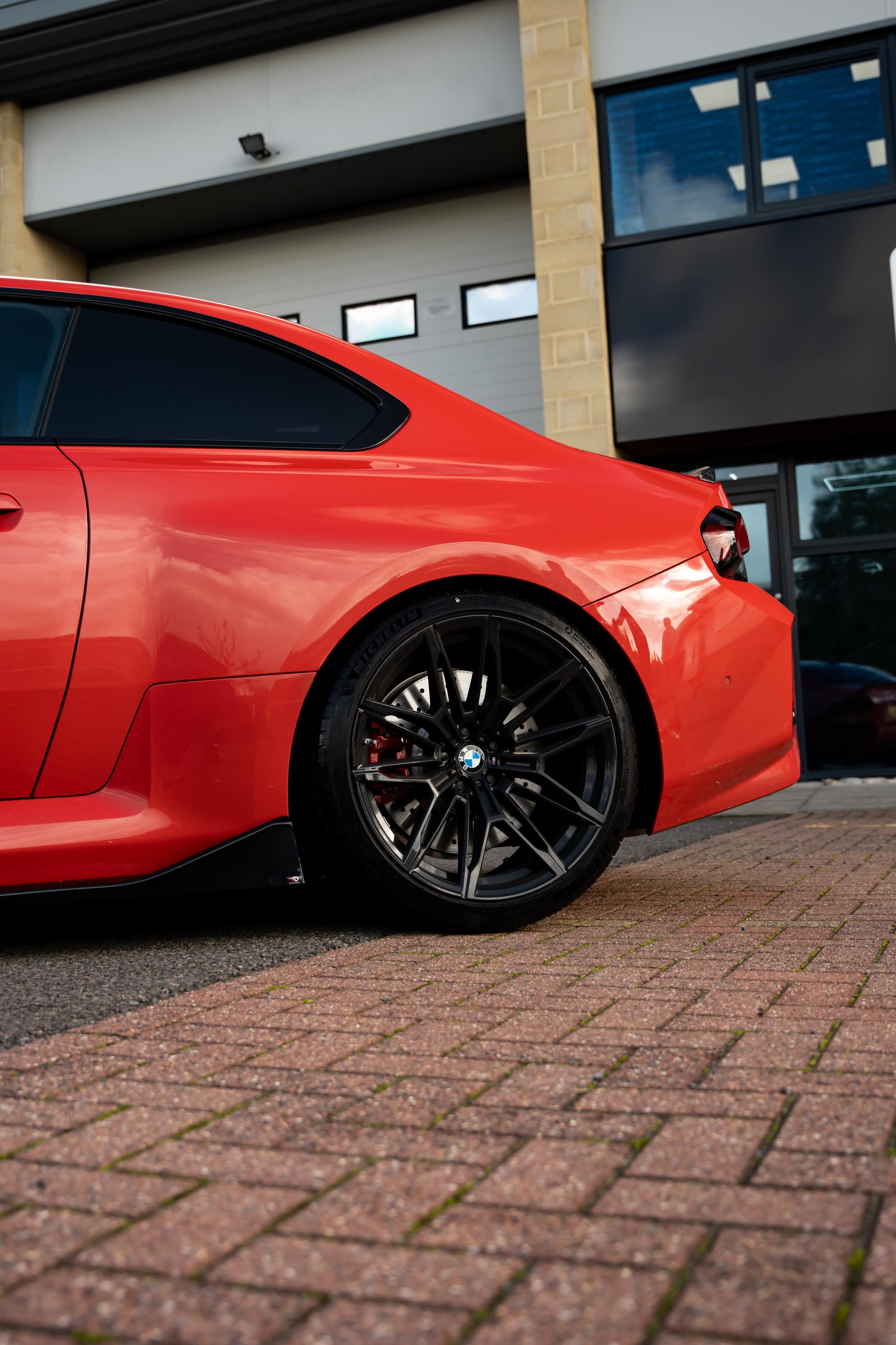 Red car parked on a brick driveway in front of a building