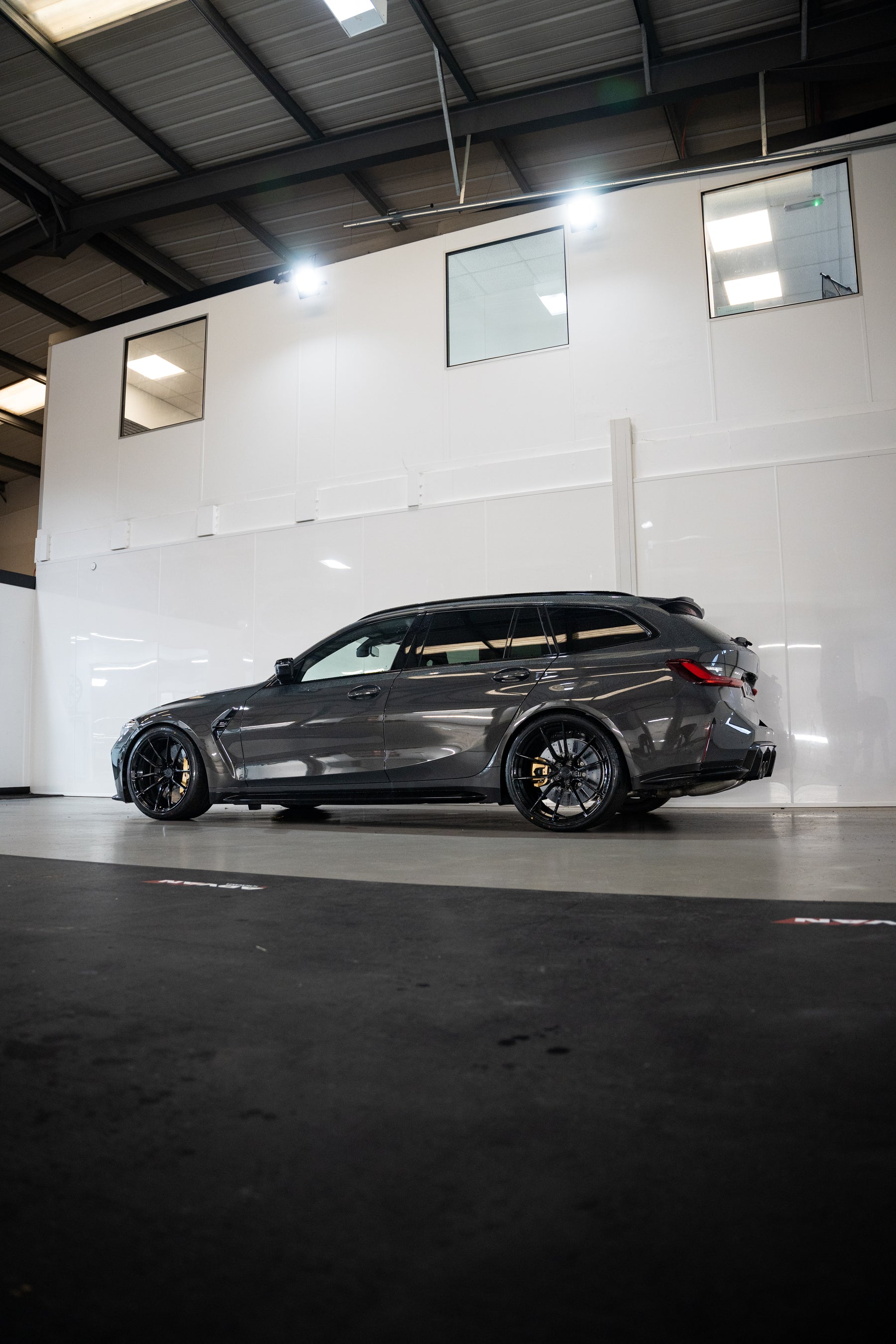 Grey G81 M3 Touring with M-W4's, Motech Stance Springs in a car workshop.
