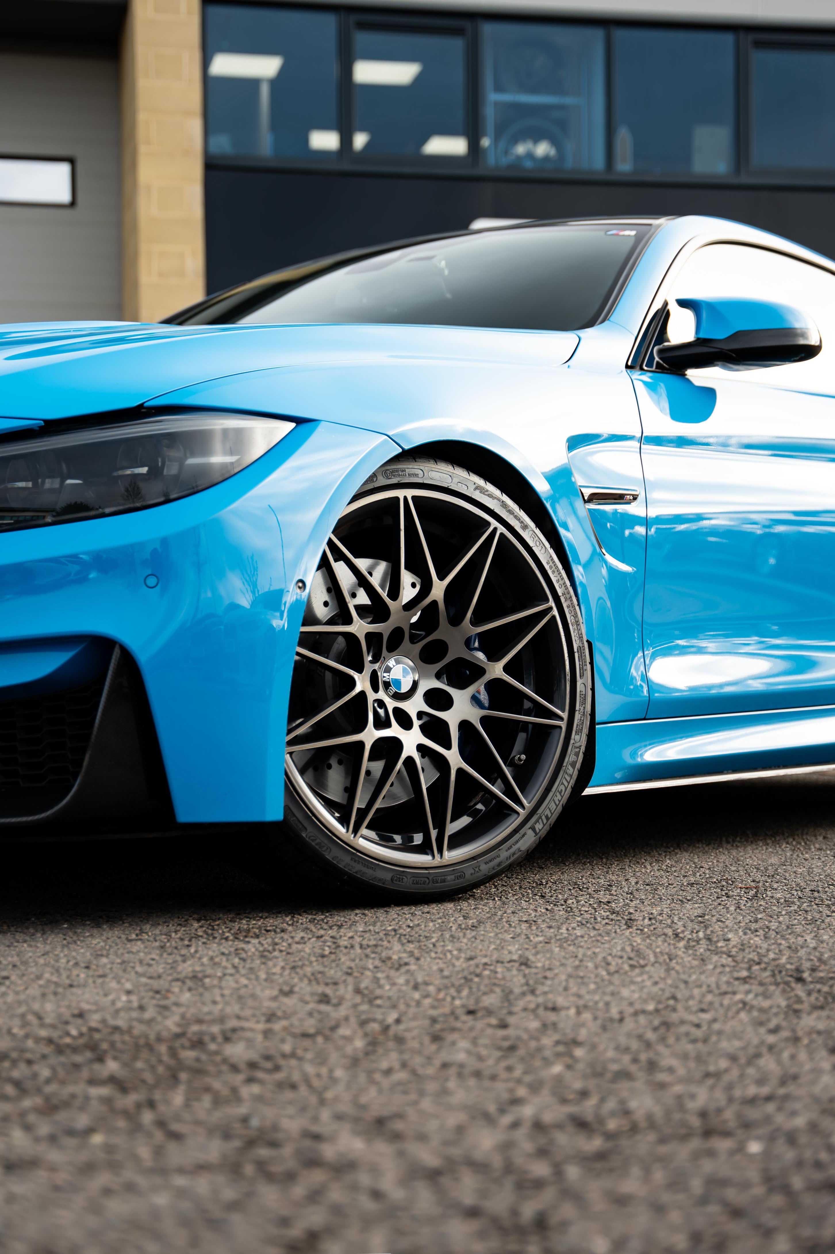 Blue car with black rims on a road, brand 'Motech' visible