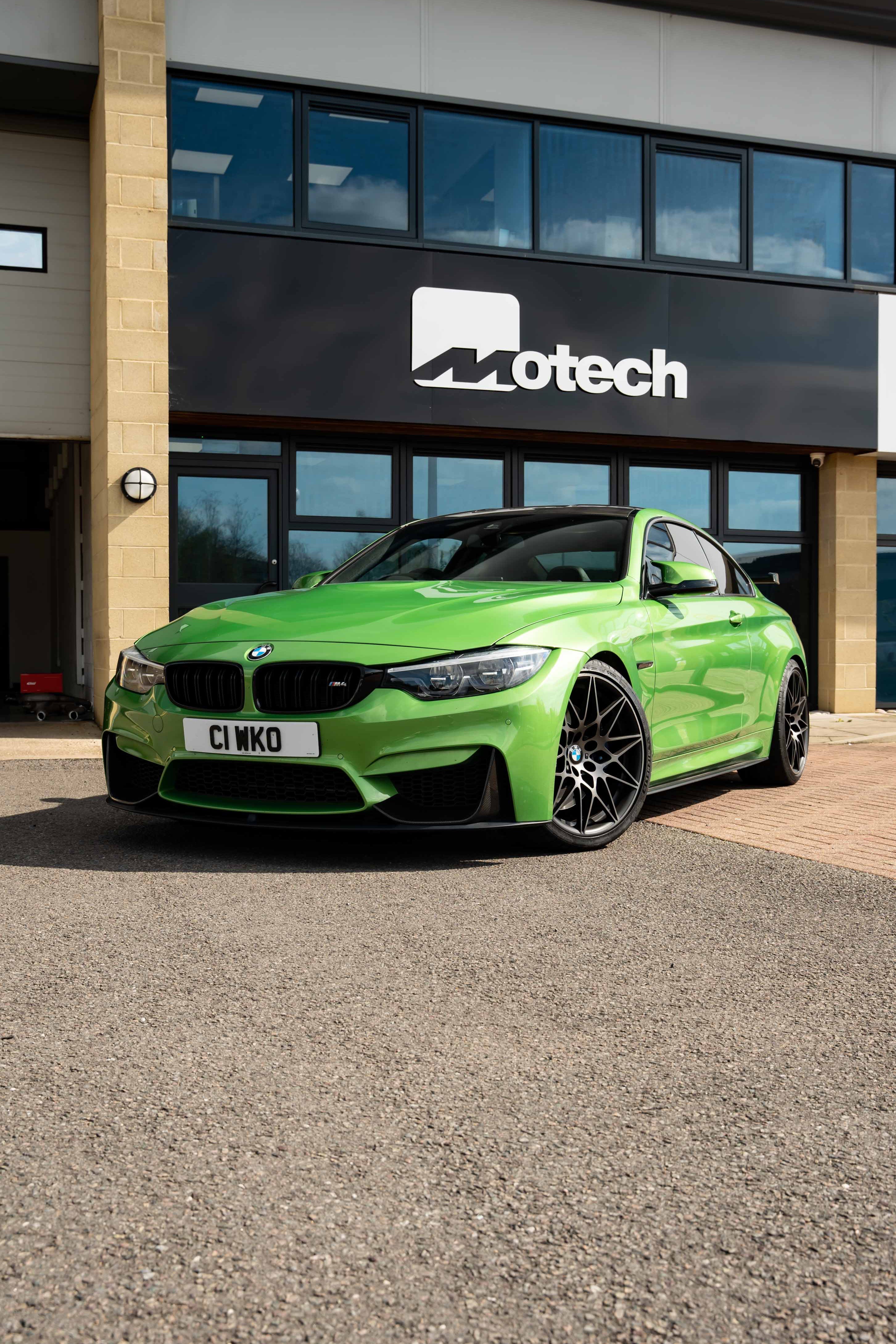 Green BMW car on Motech Stance Springs parked in front of a building with 'Motech' branding.