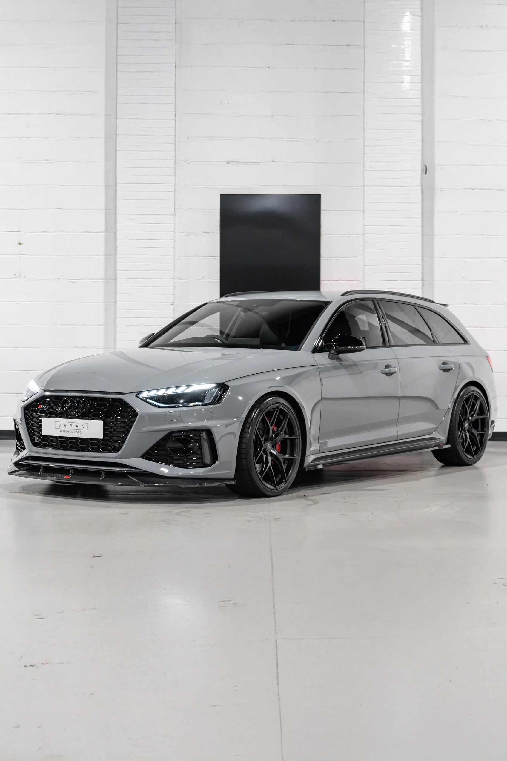 Grey Audi RS4 with Carbon Styling parked in a showroom with white walls and floor.