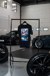 Treadlight Collection Stone Washed T-Shirt with graphic design on a rack in a garage setting with cars and tires.