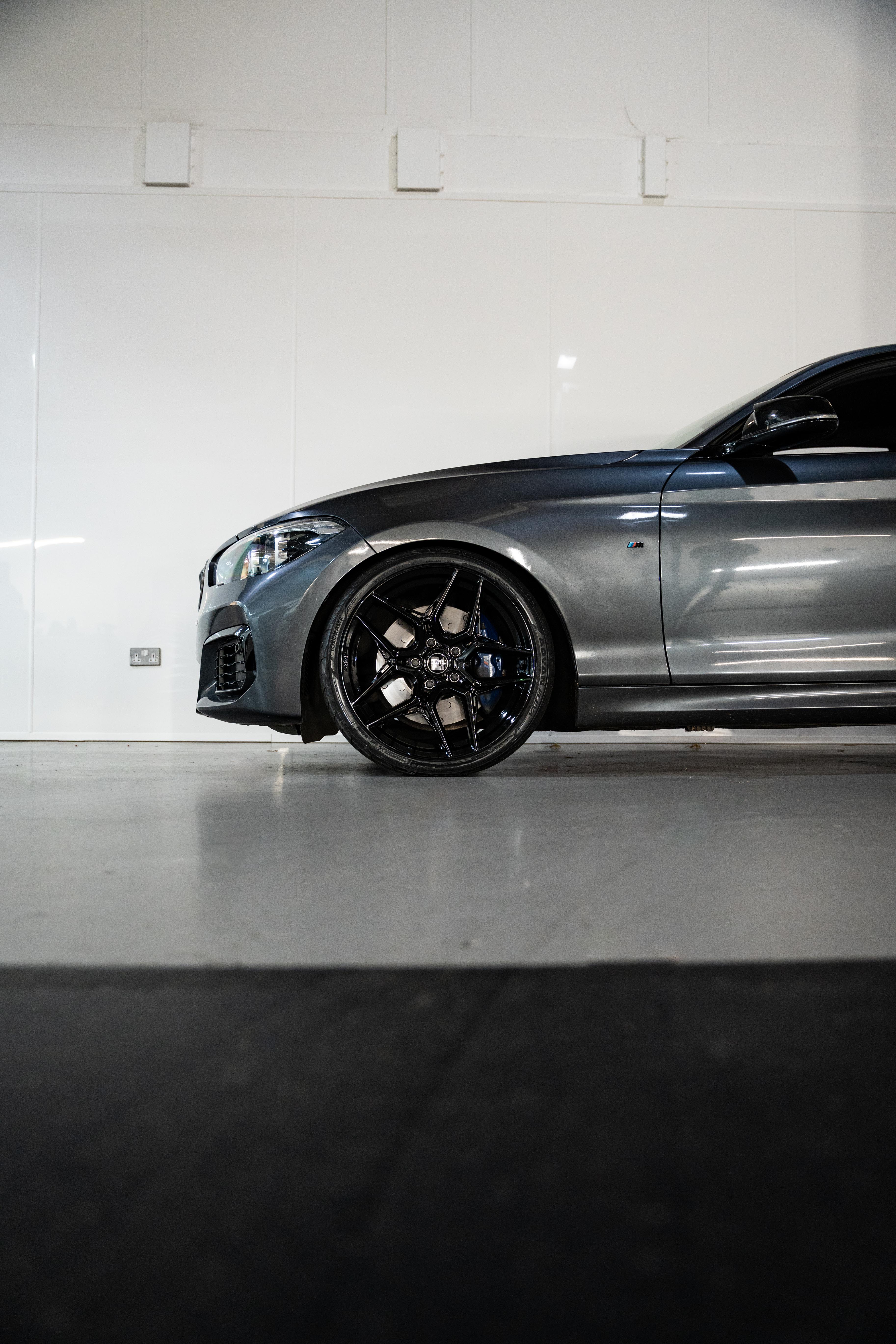 Front of a Grey BMW with Precision Black M-W1's in a workshop.