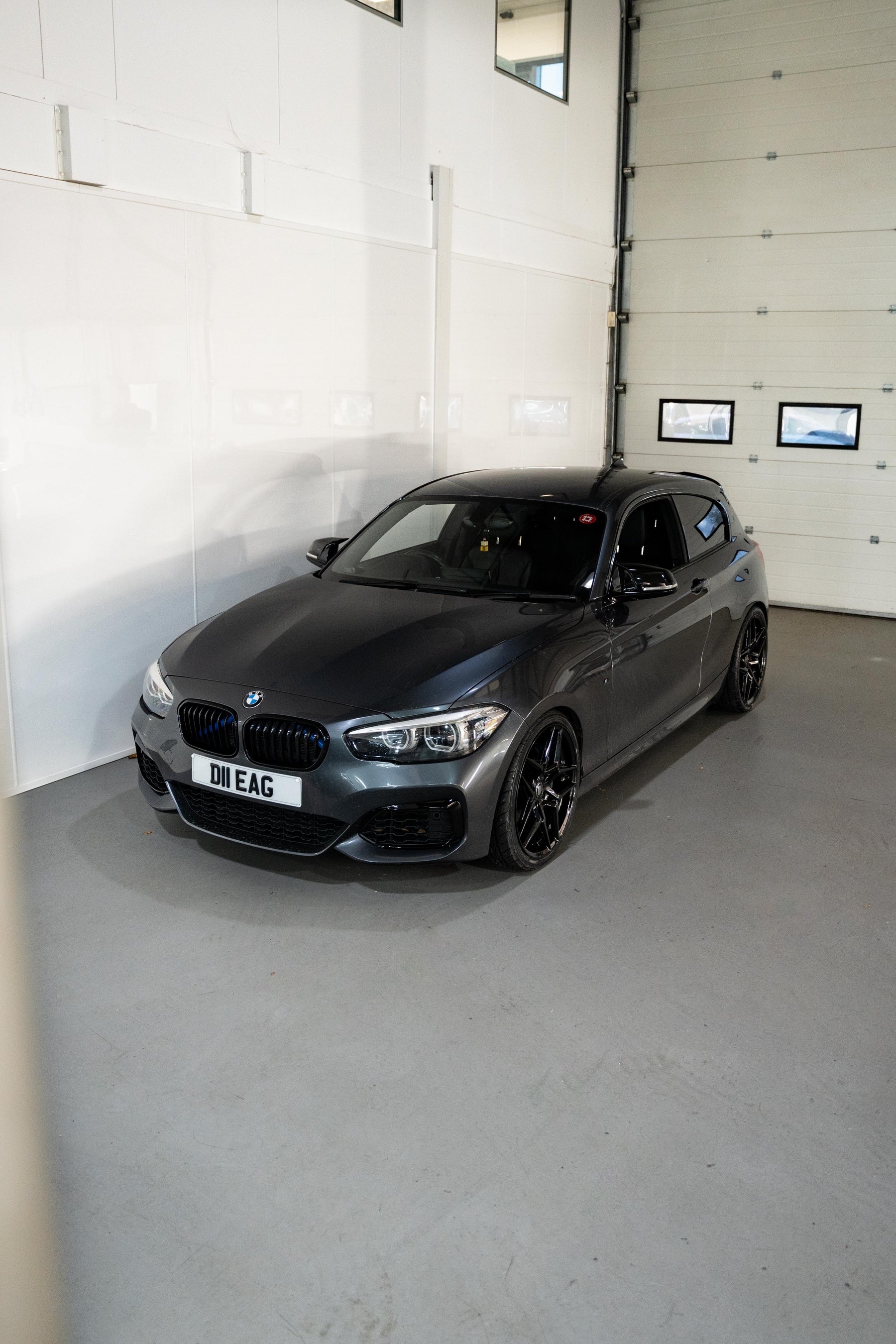 Silver BMW 1 Series on Motech Stance Springs parked inside of a workshop.