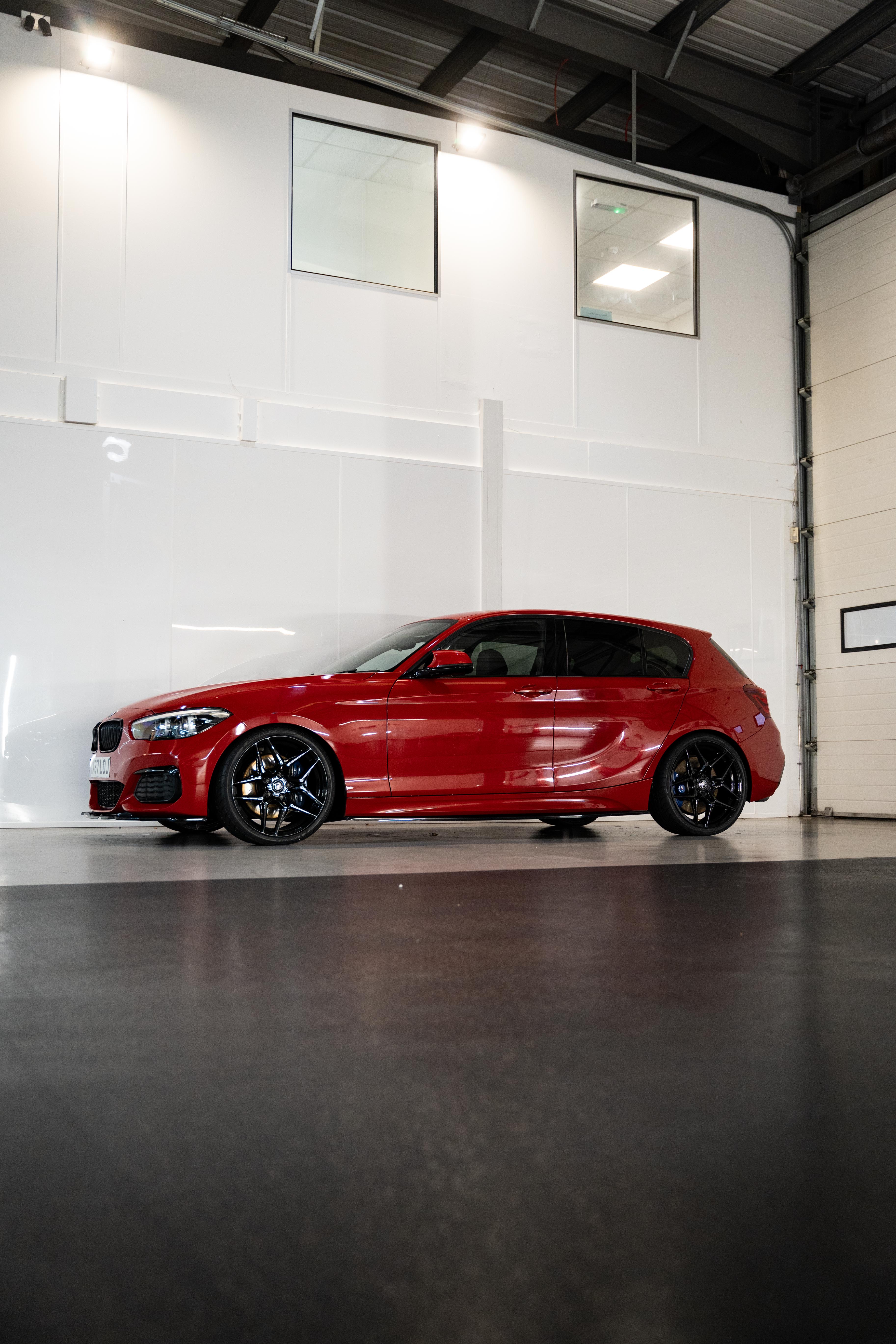 Side-on shot of a Red BMW with Precision Black M-W1 wheels in a workshop.