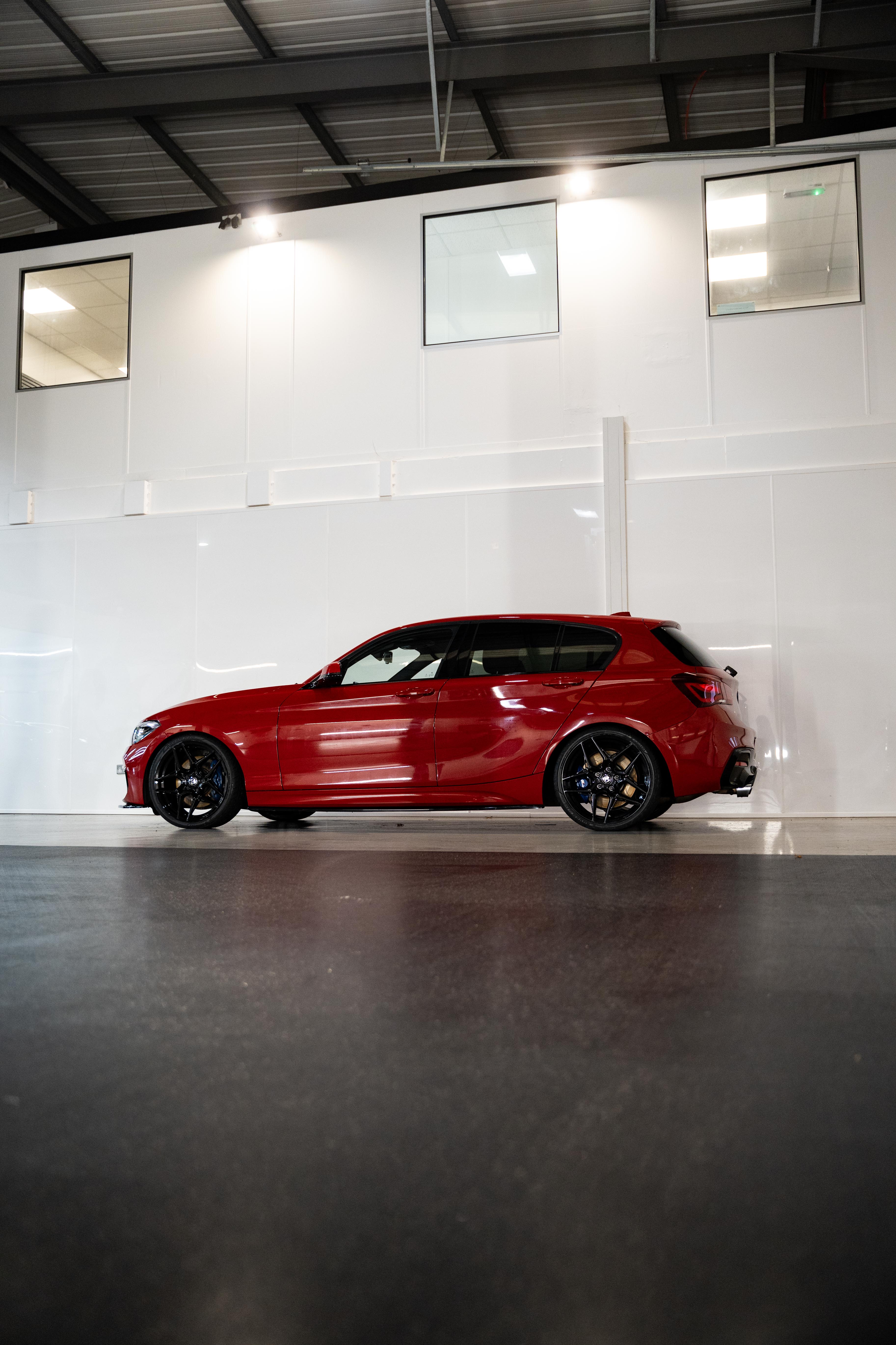 Side-on shot of a red BMW with Precision Black M-W1 wheels in a workshop.