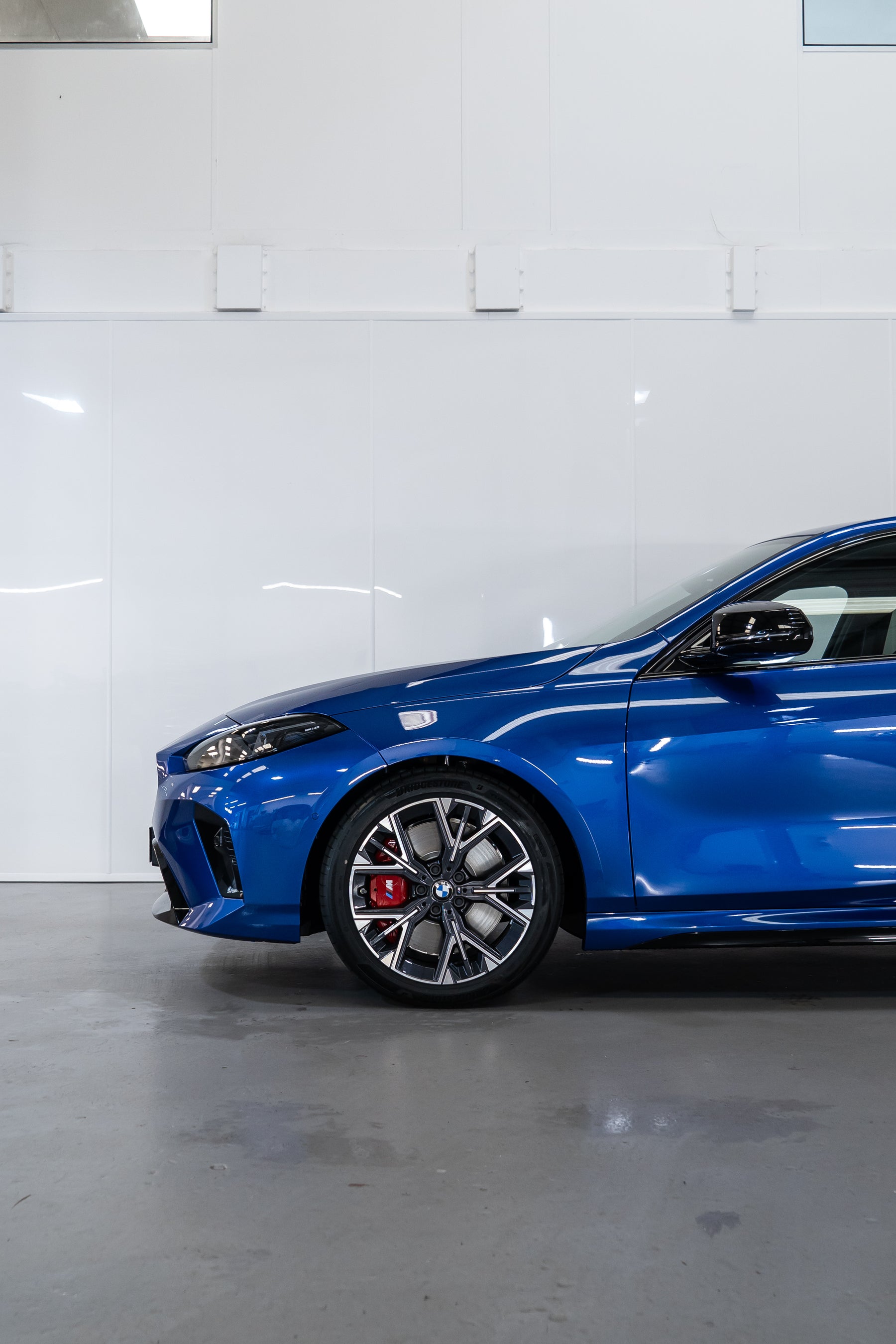 Front of a Blue BMW F70 with Motech stance springs parked in a workshop.