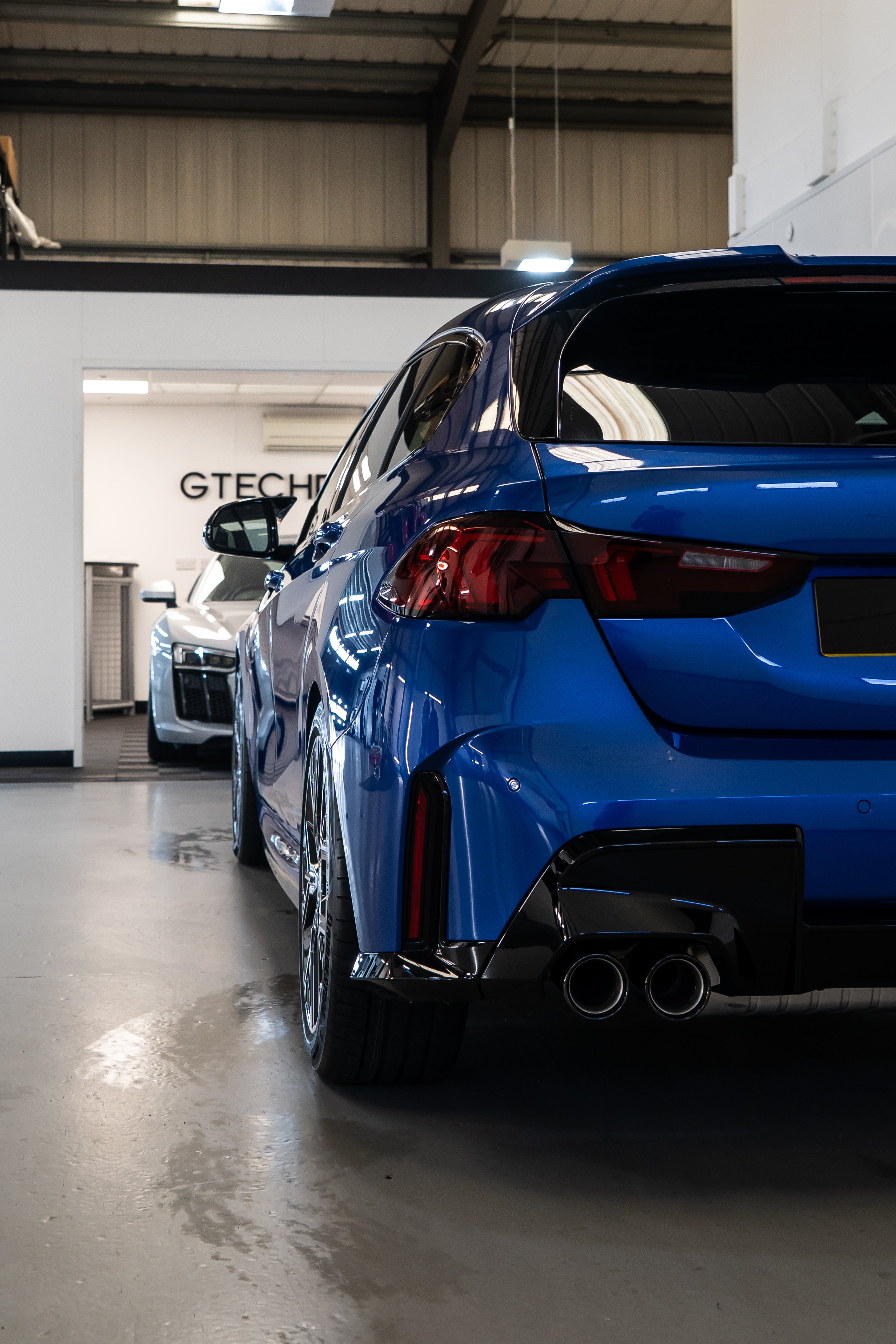 Rear shot of a Blue BMW F70 with Motech stance springs parked in a workshop.