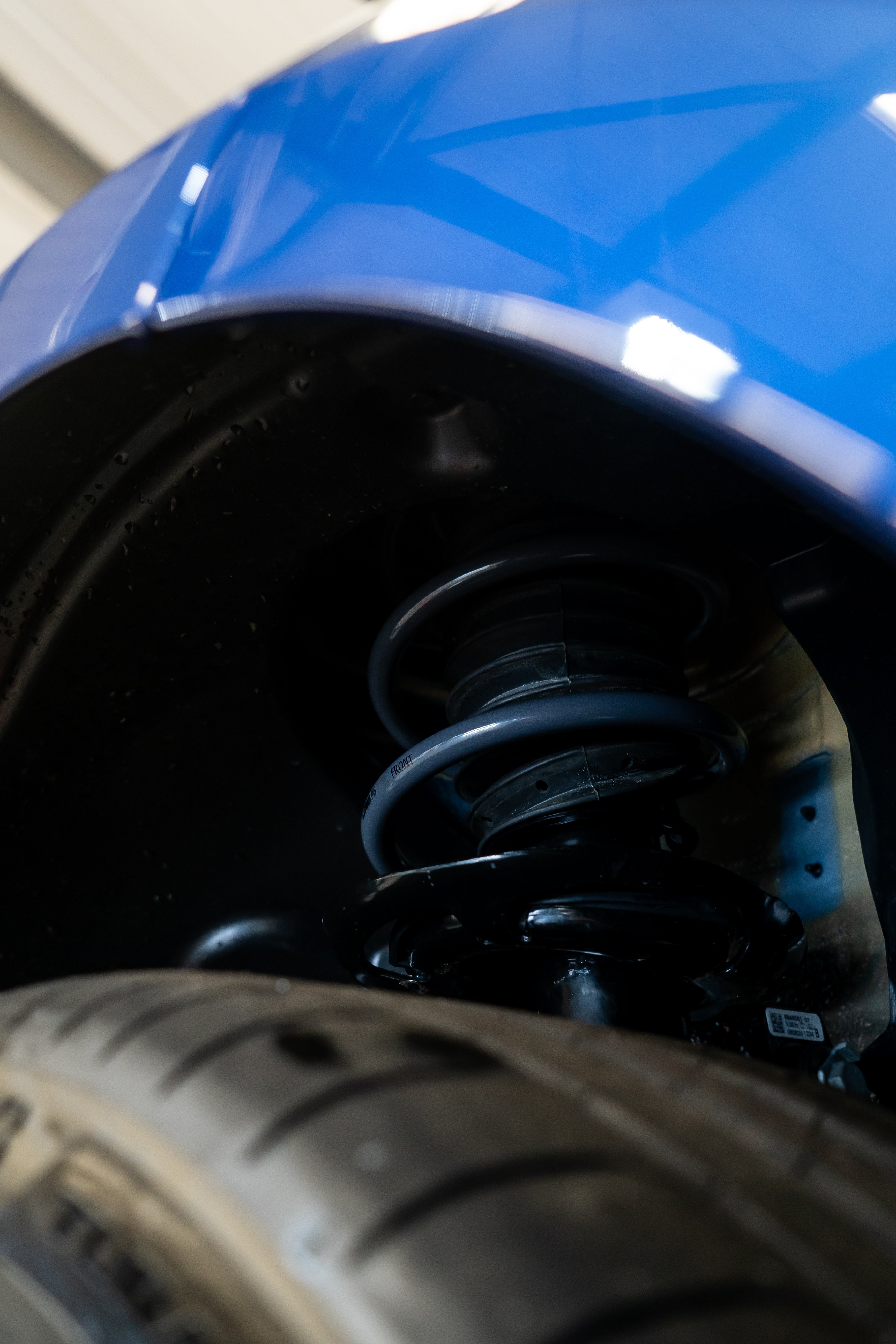 Close-up of lowering springs being fitted on a blue car