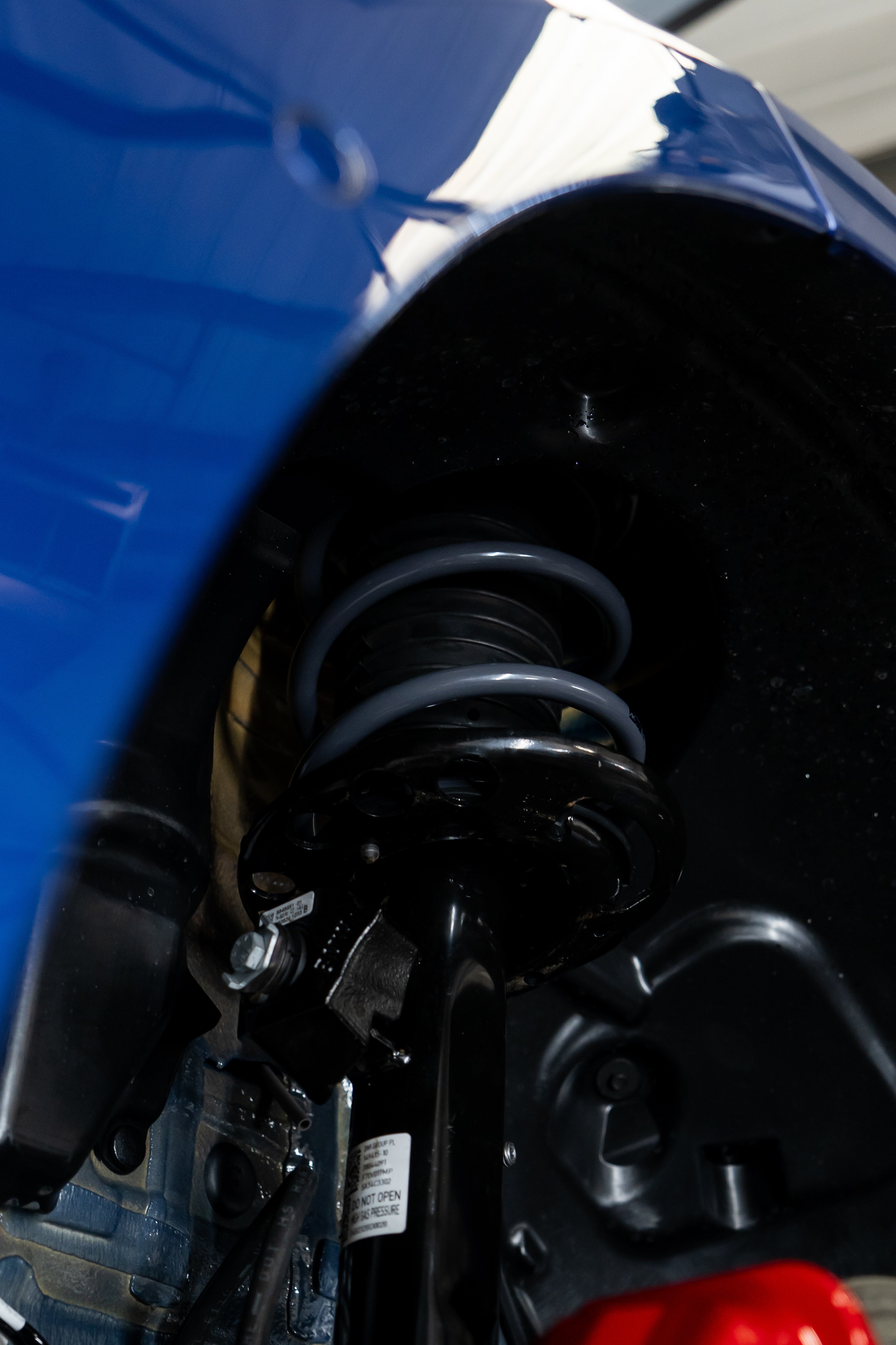Close-up of lowering springs being fitted on a blue car