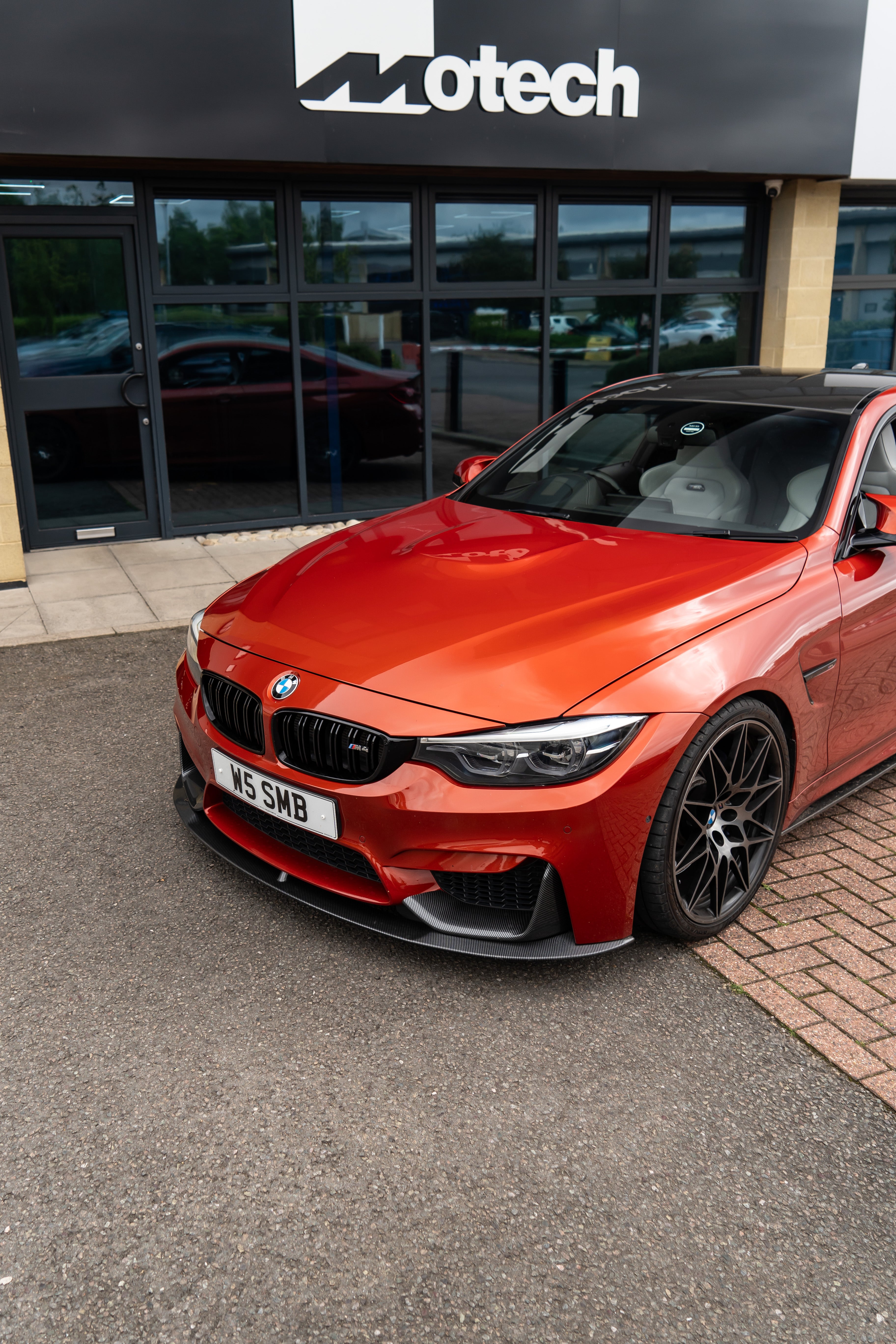 Front of a Red BMW M4 on Motech stance springs parked outside 'Motech' building