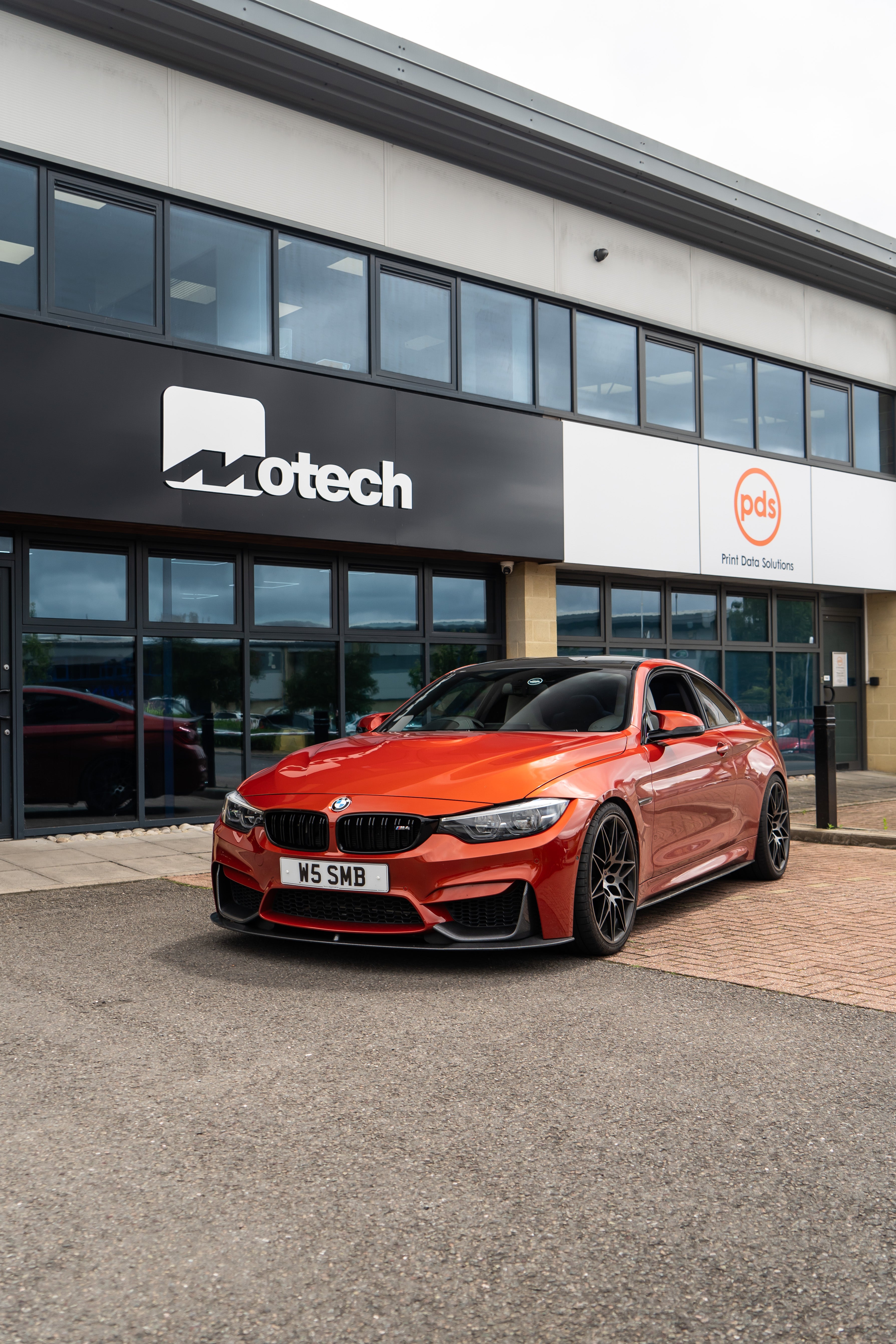 Red BMW M4 on Motech stance springs parked outside 'Motech' building