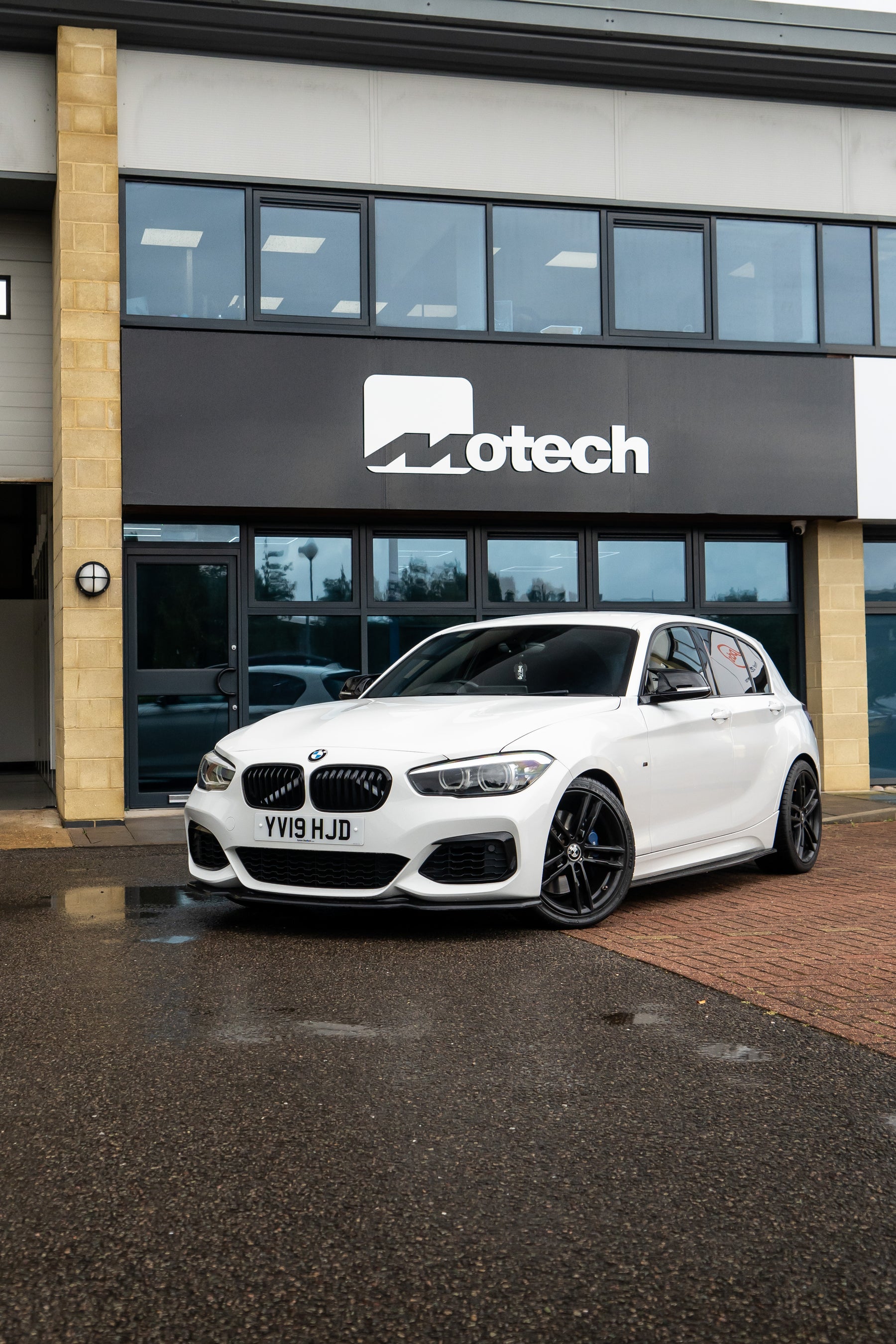 A White BMW 1 Series with Motech stance springs outside the Motech building.