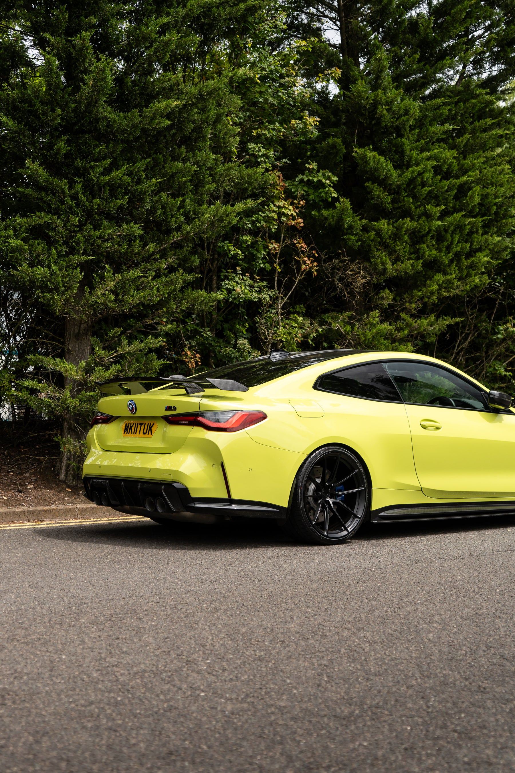 Back of a São Paulo Yellow BMW M4 on Motech Stance Springs parked in front of some trees.