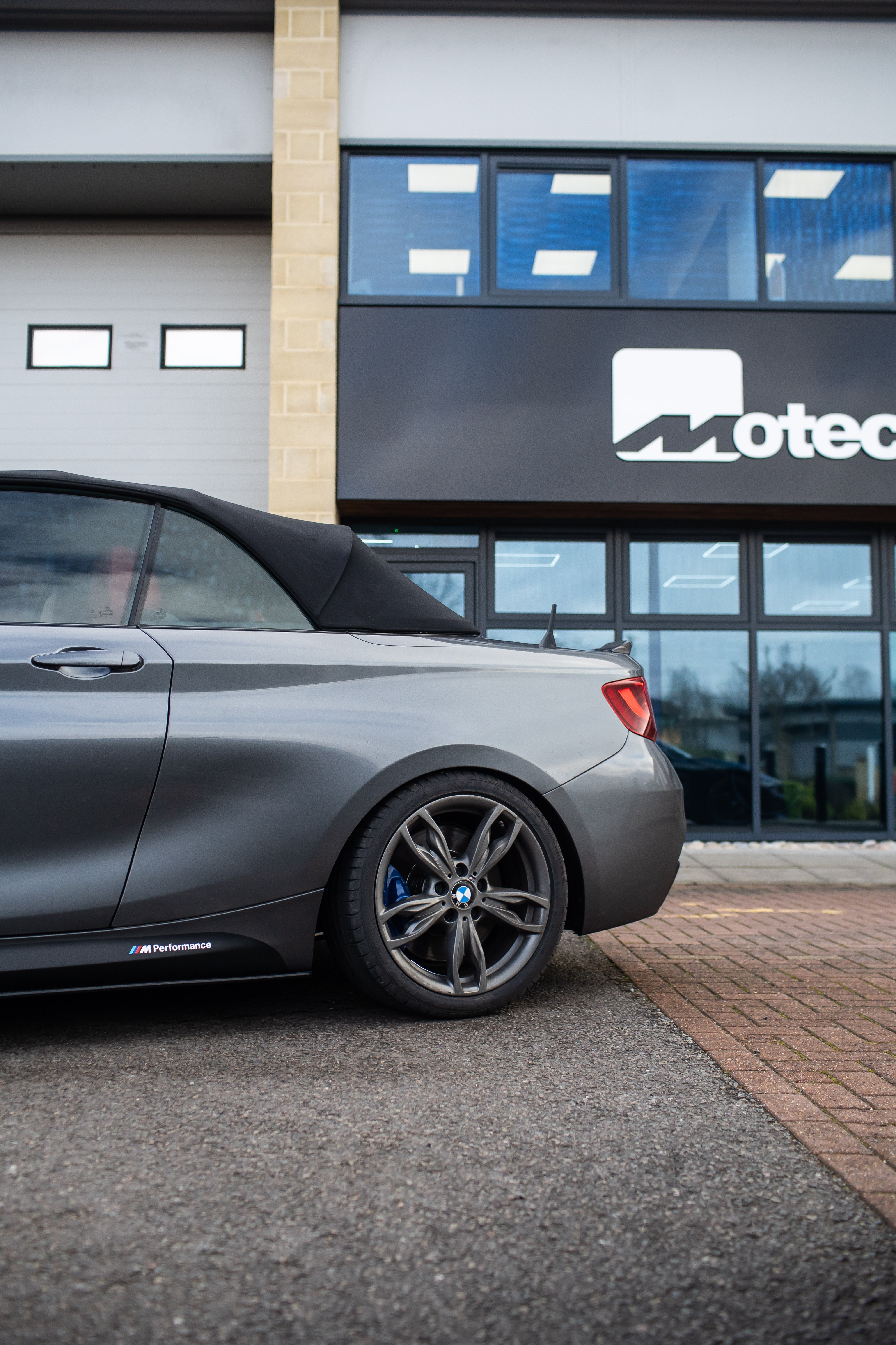Back of a Grey BMW 2 Series on Motech Stance Springs parked outside the Motech building.