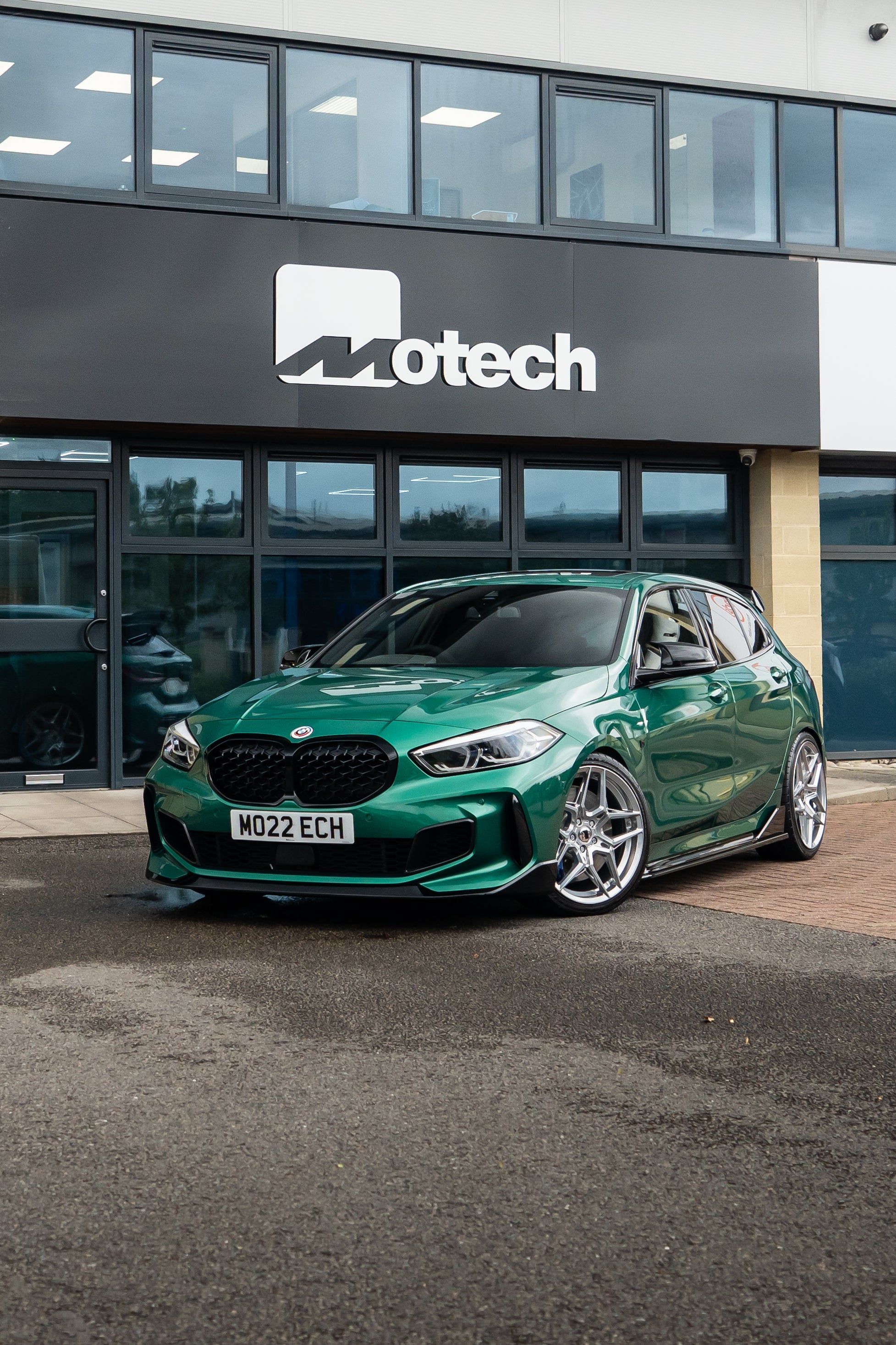 Green 1 Series on Motech Stance springs parked outside a building with 'Motech' branding.