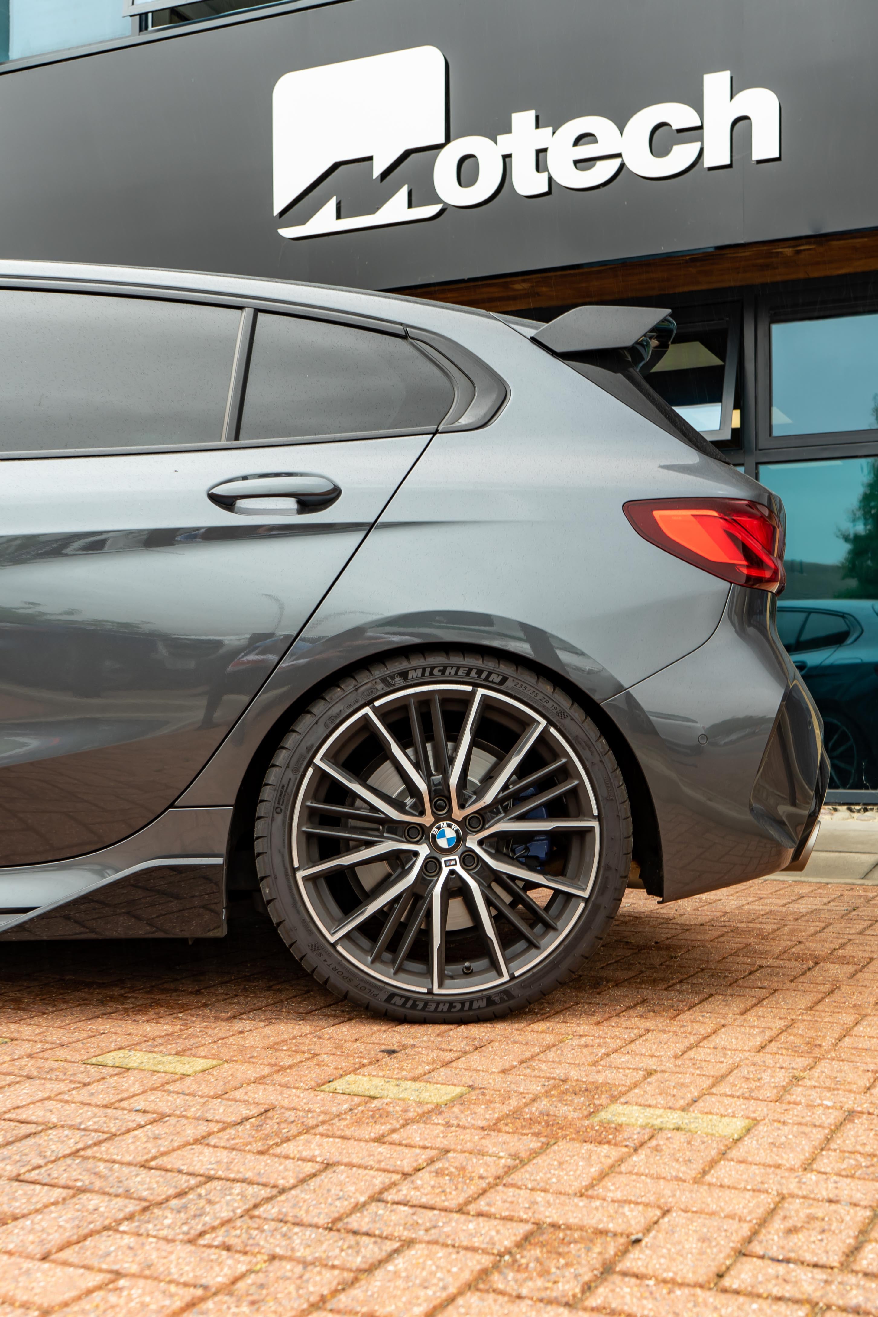 Back of a Grey car parked in front of a building with 'Motech' branding.