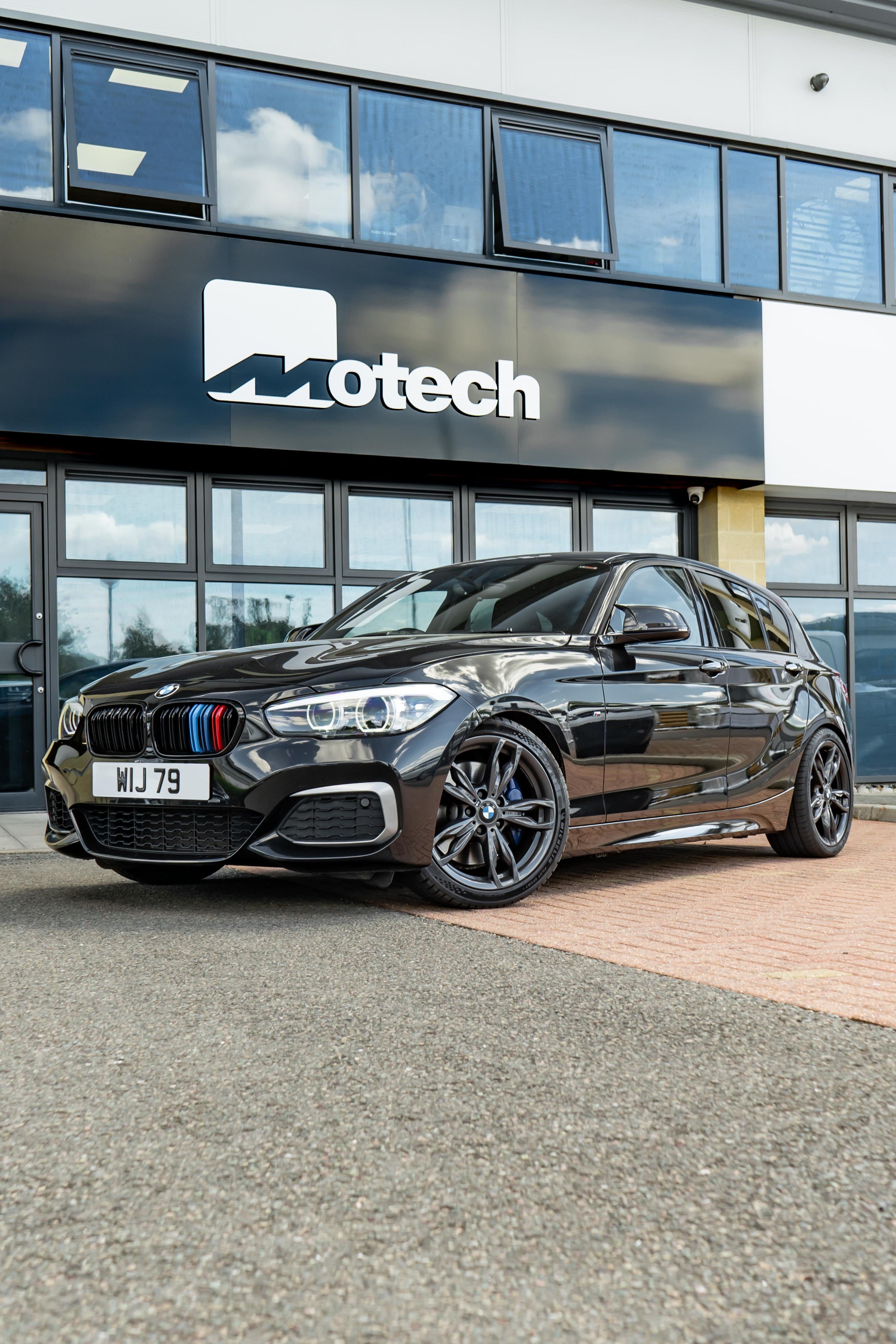 Black BMW 1 Series on Motech Stance Springs parked outside a building with 'Motech' branding.