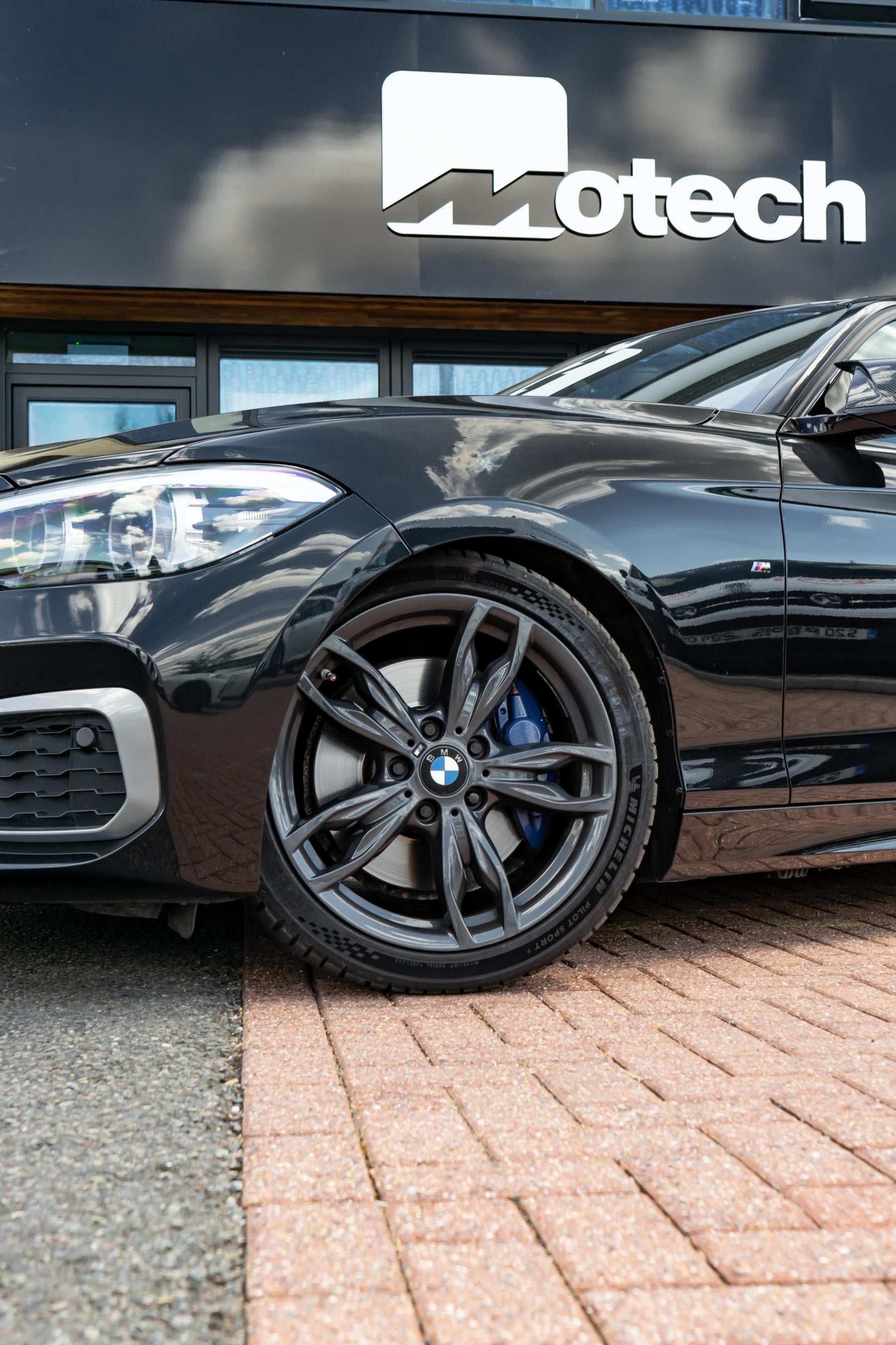Black BMW parked in front of a building with 'Motech' branding.