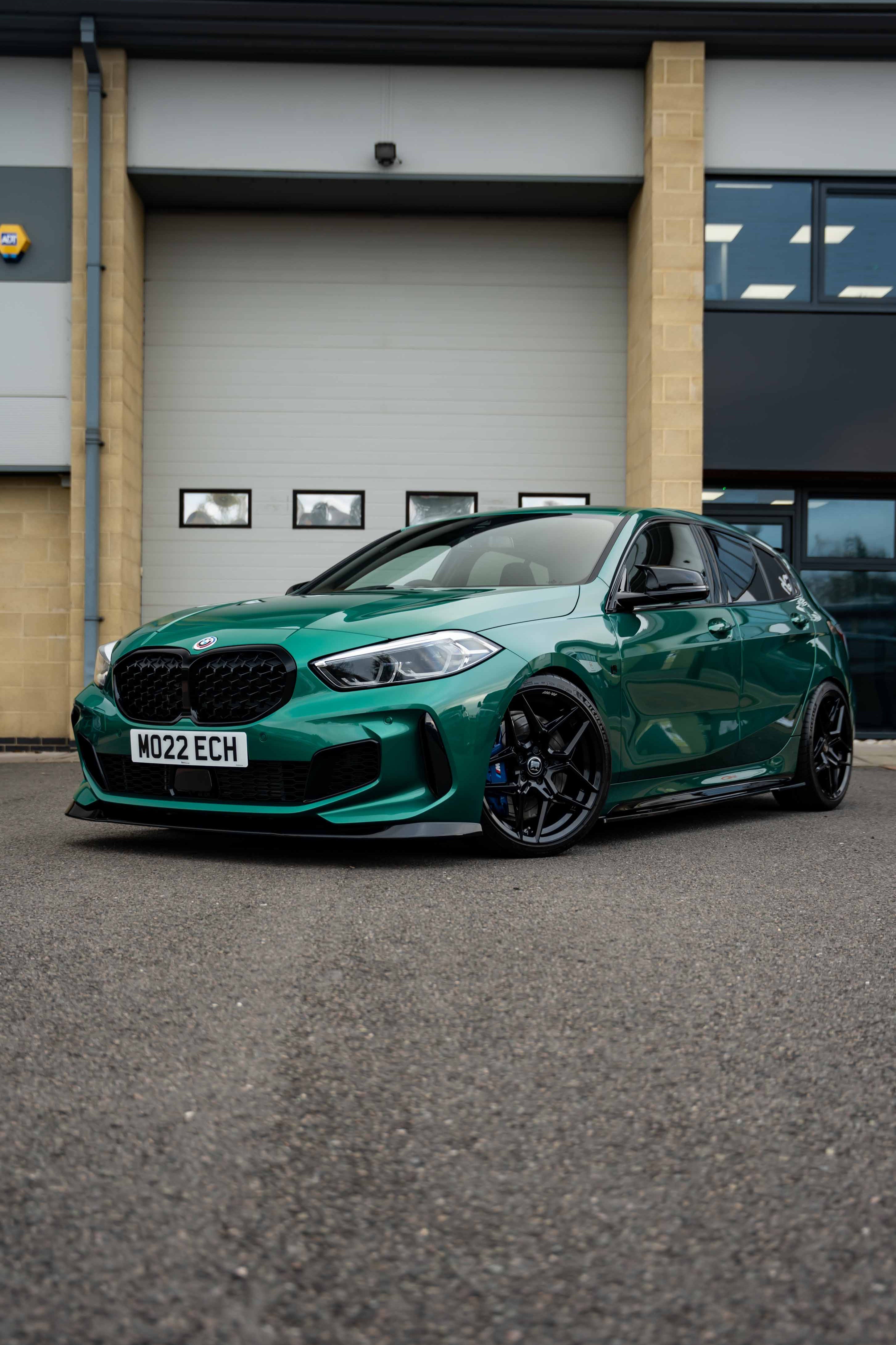 Green BMW car on Motech Stance Springs parked in front of a building with 'Motech' branding.