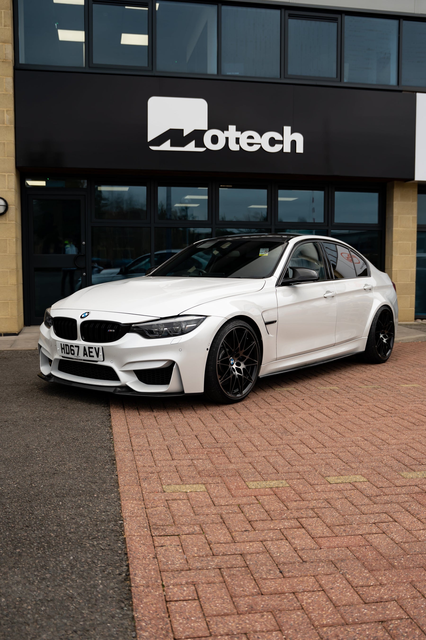 White BMW car parked in front of a building with 'Motech' branding.
