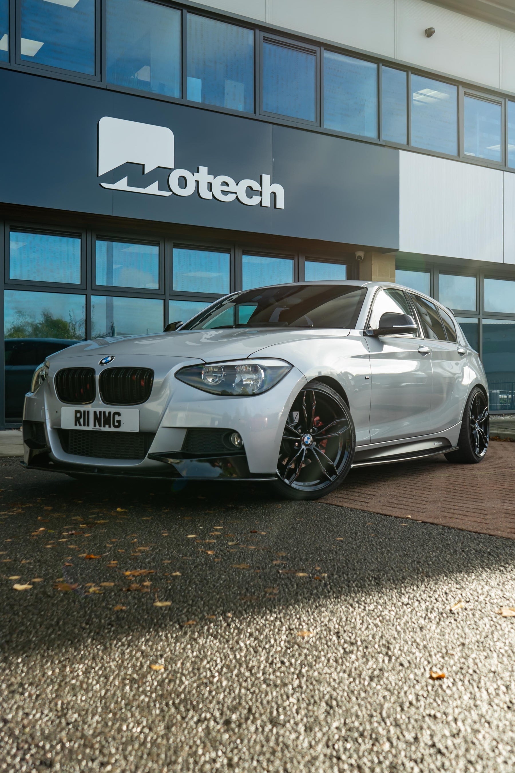 Grey BMW on Motech Stance Springs parked outside a building with 'Motech' branding.