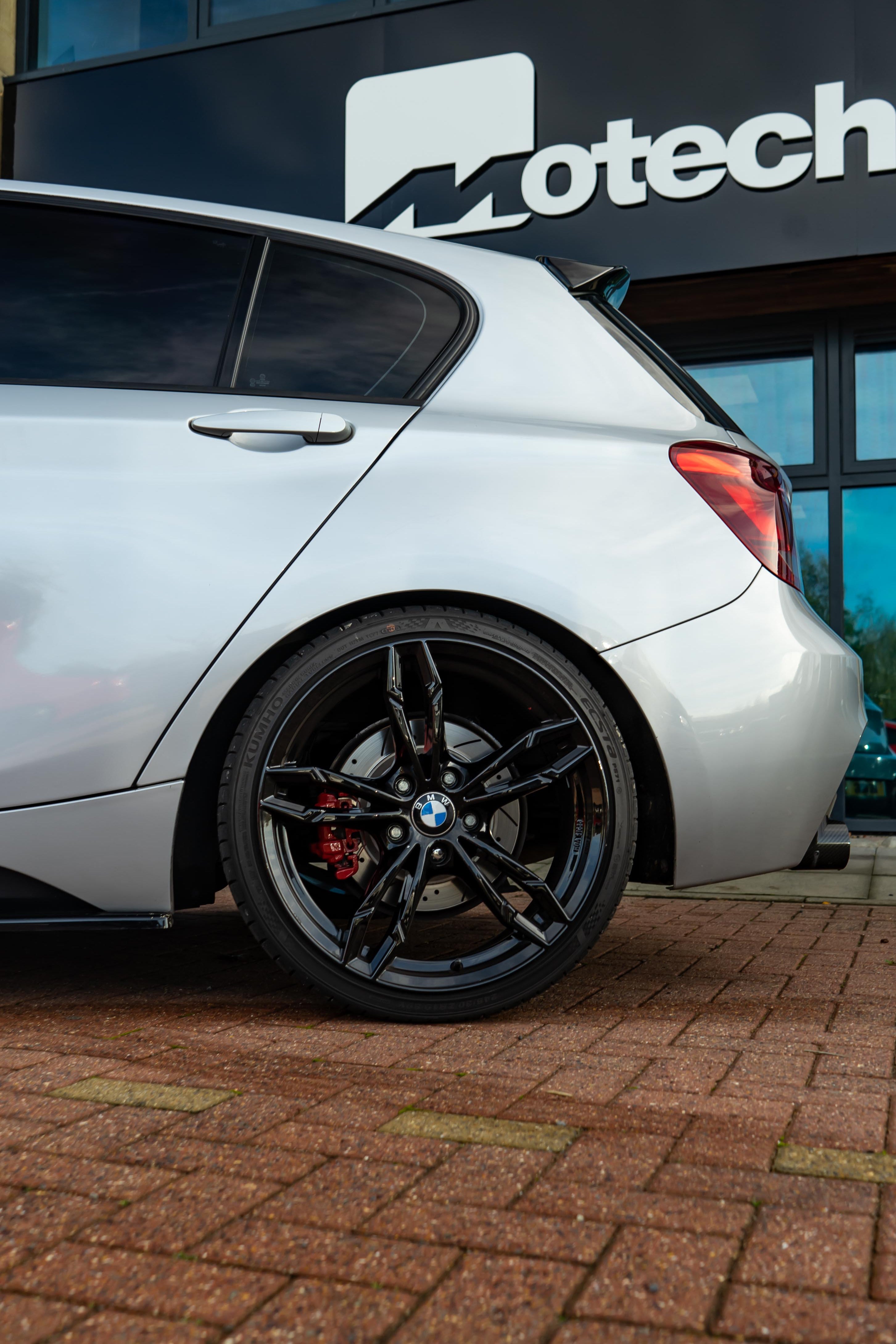 Back of a Grey BMW on Motech Stance Springs parked outside a building with 'Motech' branding.