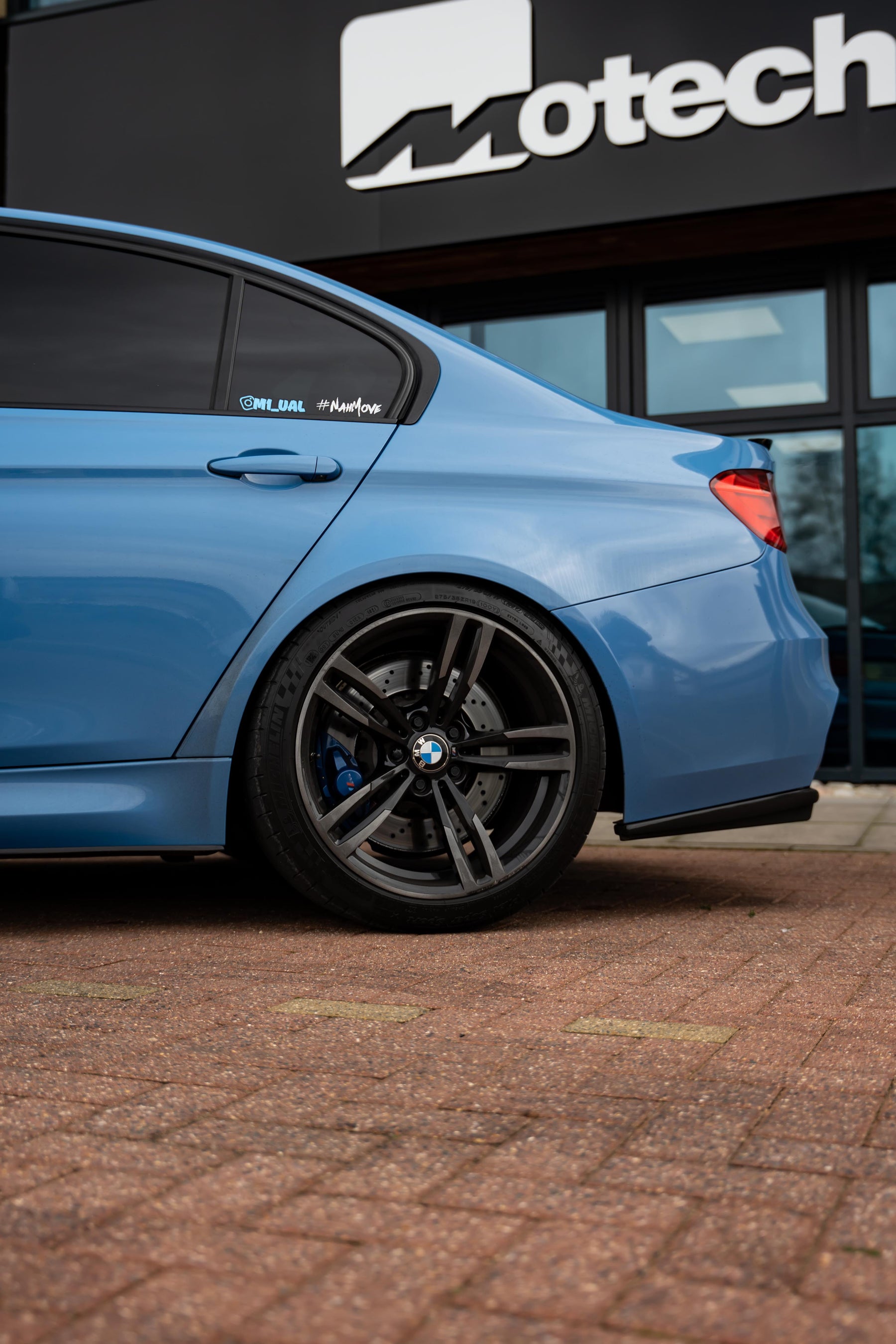 Blue car parked in front of a building with 'Motech' branding.
