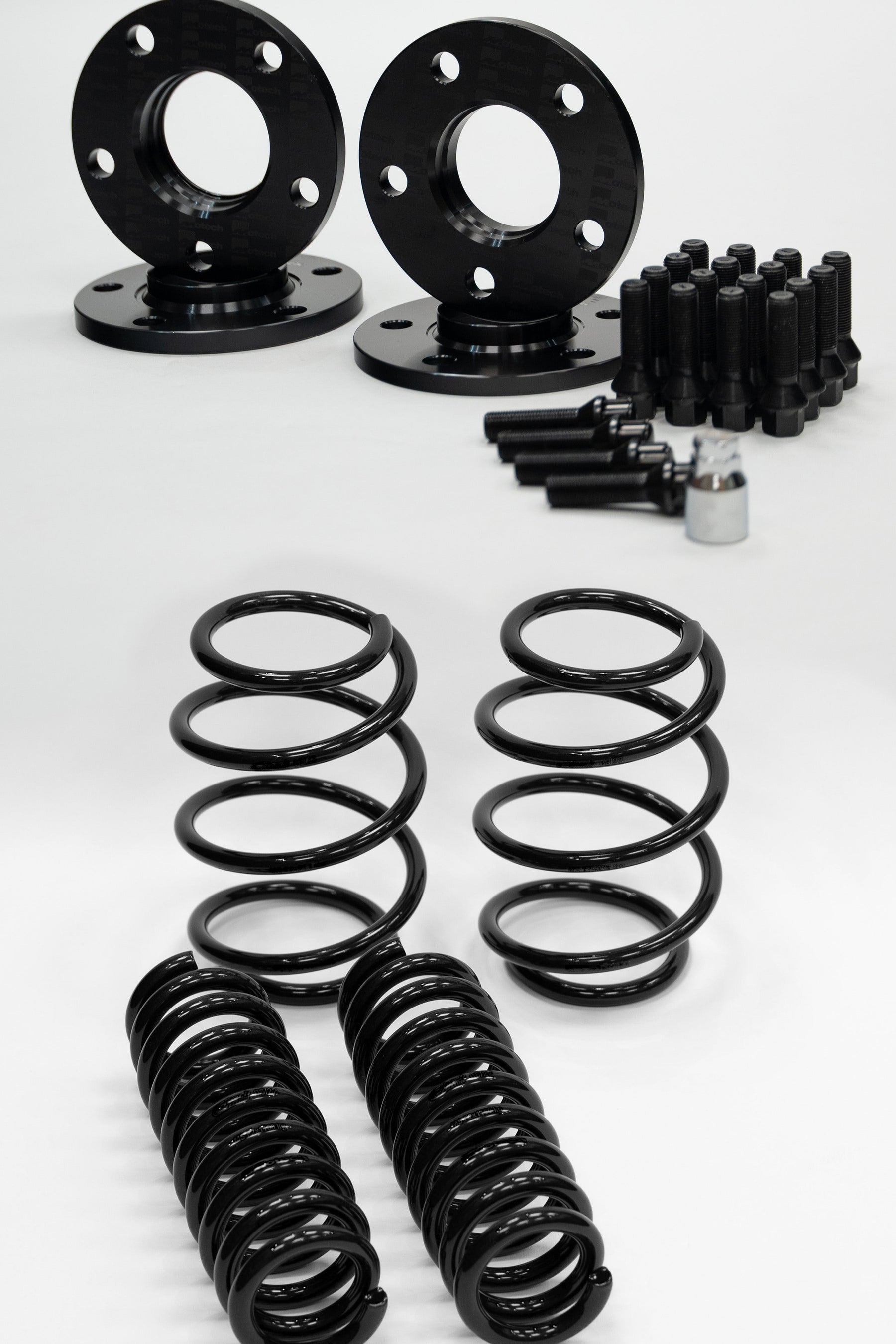 Set of black Motech wheel spacers, springs, and bolts on a white background