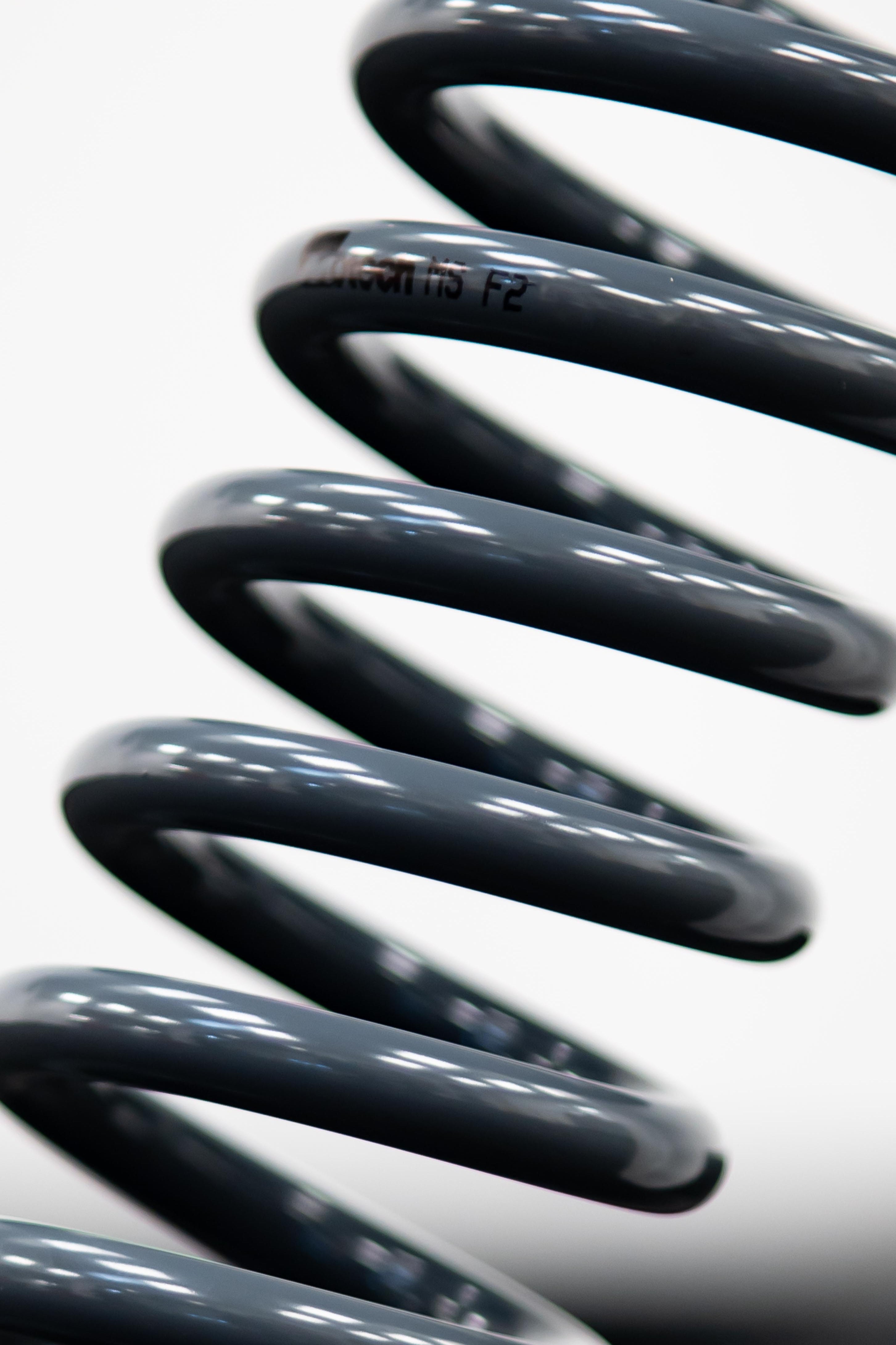 A close-up of a black Motech stance lowering spring, showing its surface and the brand name 'Motech' visible on the spring.