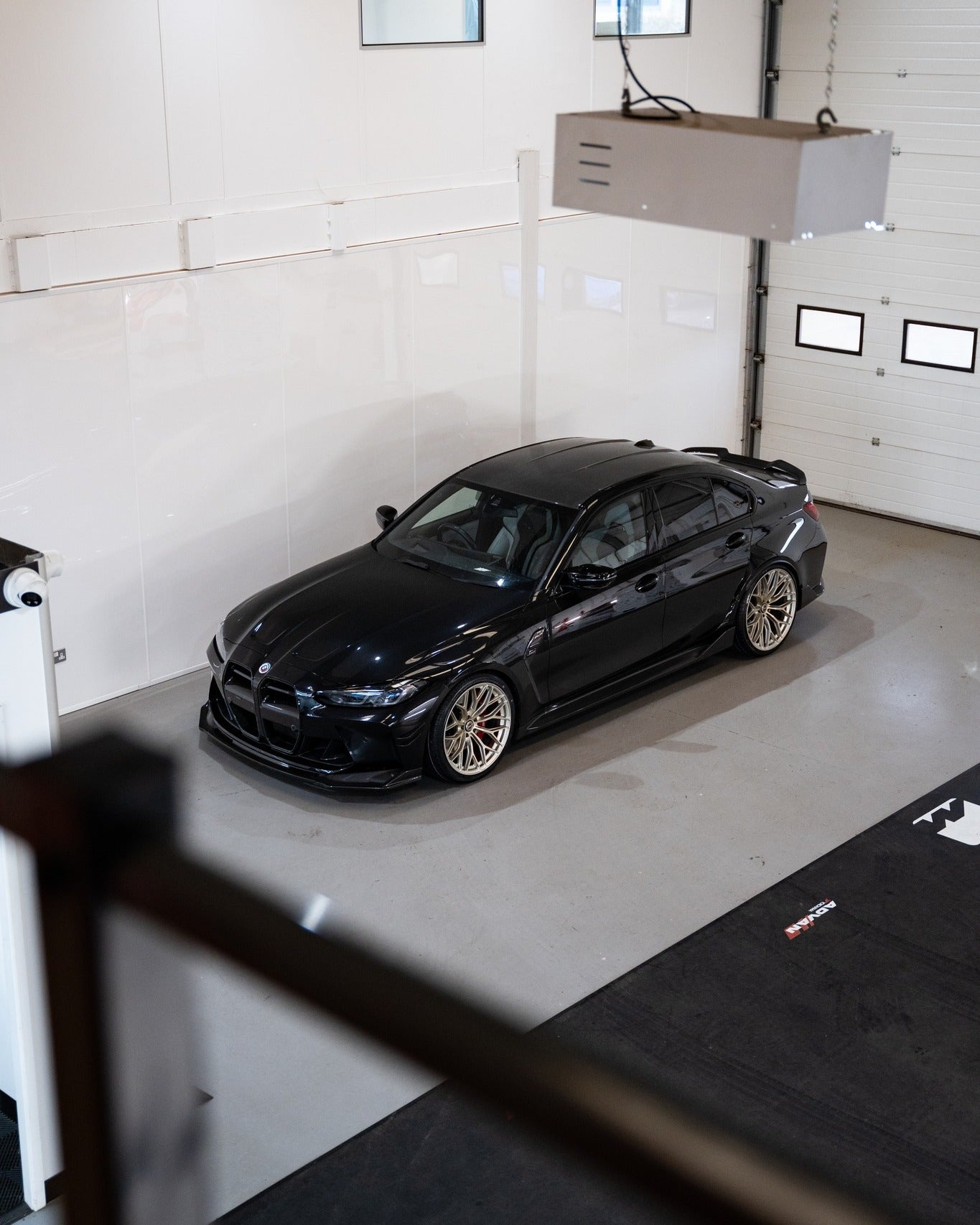 M3 G80 with Frozen Gold M-WX's and on Motech Stance springs in a car workshop. 
