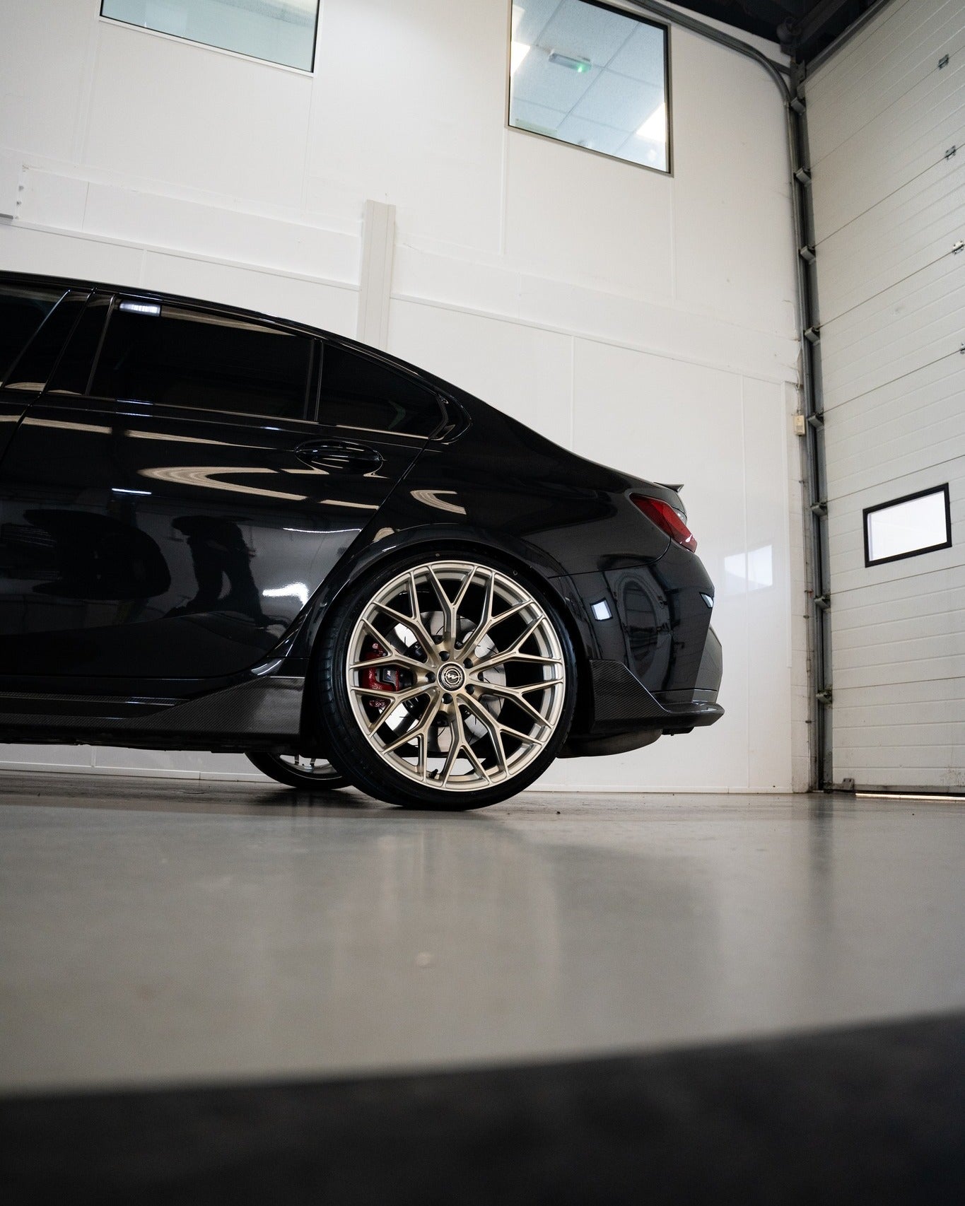 Rear shot of an M3 G80 with Frozen Gold M-WX's and on Motech Stance springs in a car workshop. 