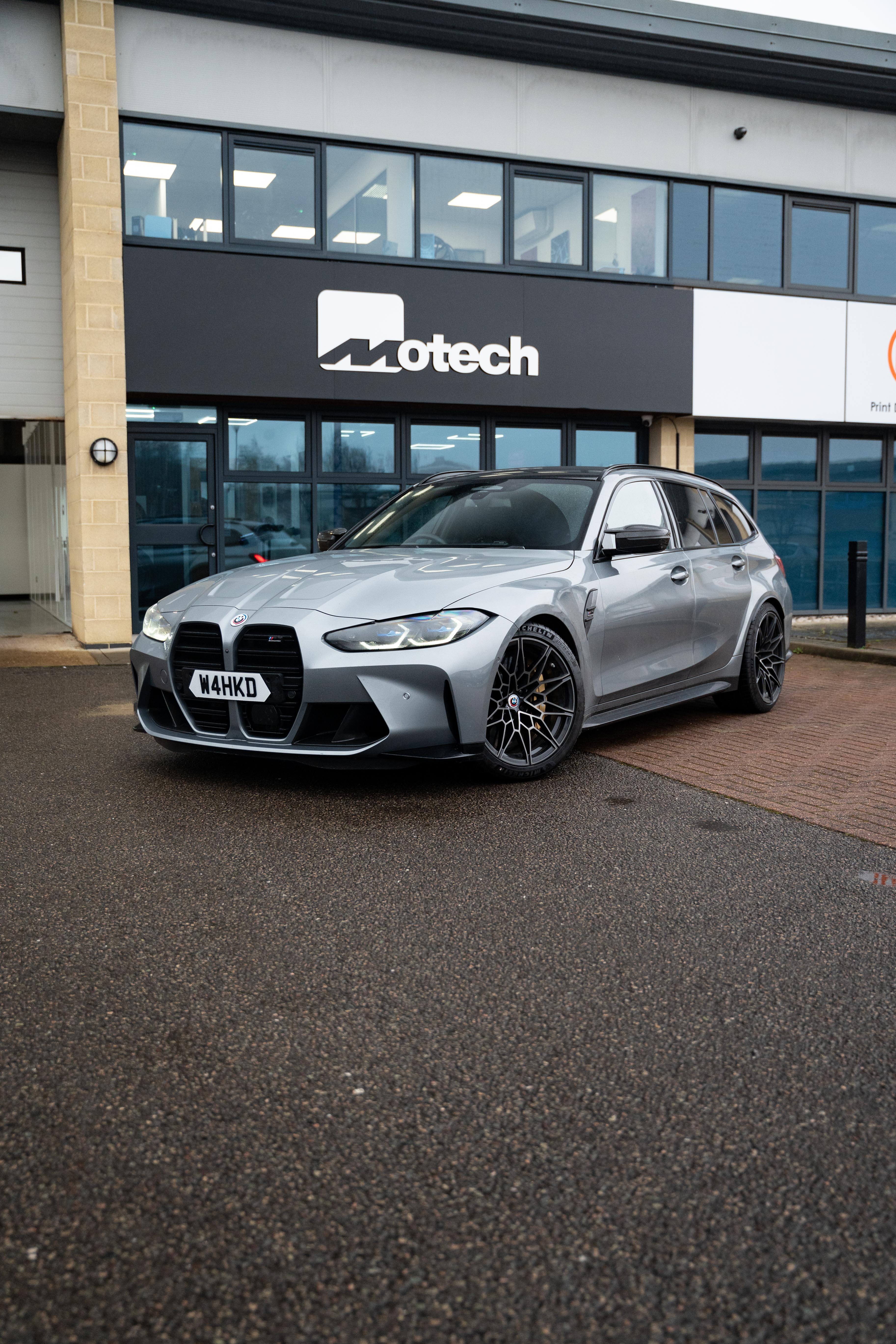 Grey BMW M3 on Motech Stance springs outside a building with 'Motech' branding.