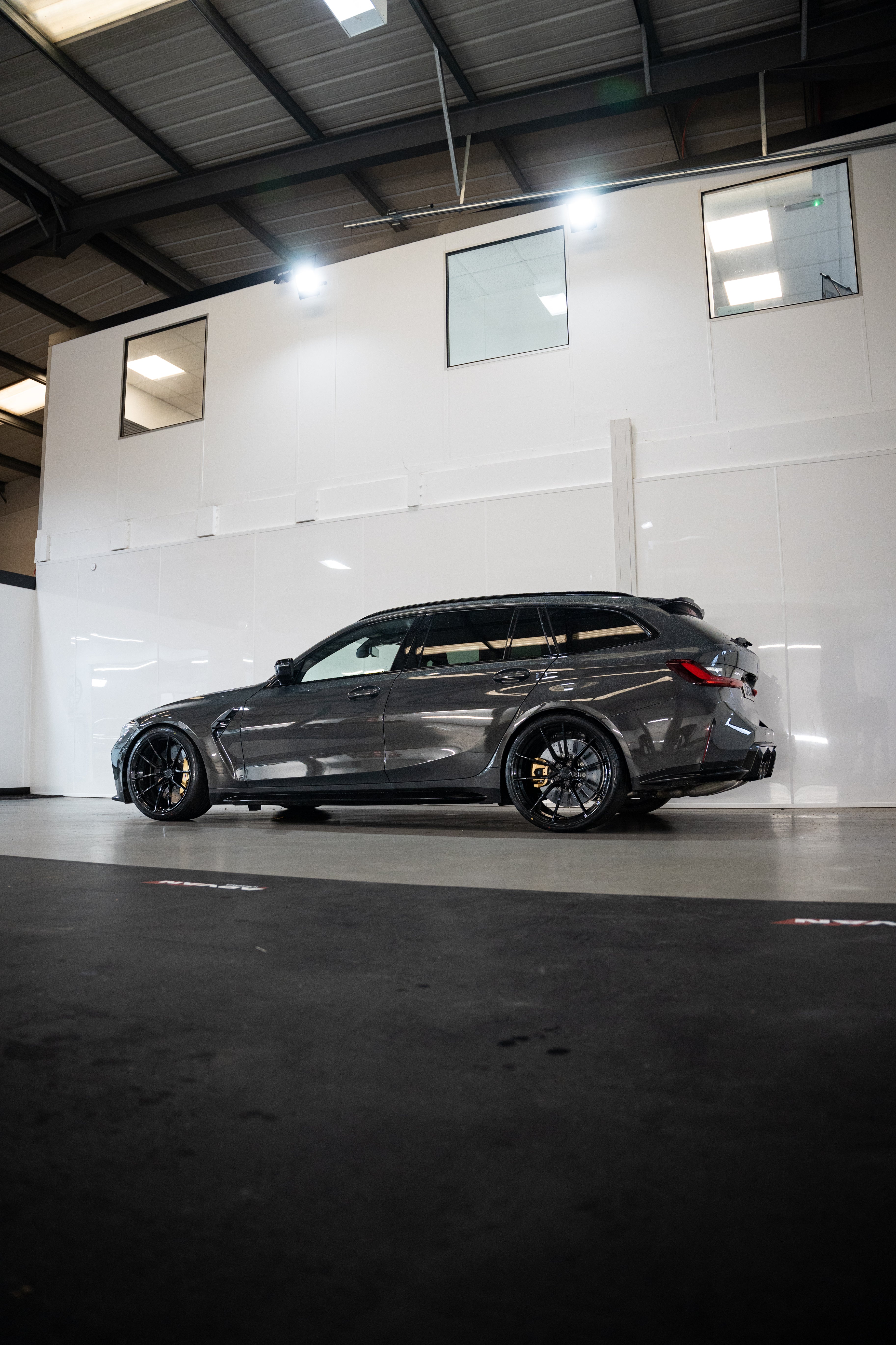 Grey G81 M3 Touring with M-W4's, Motech Stance Springs in a car workshop.