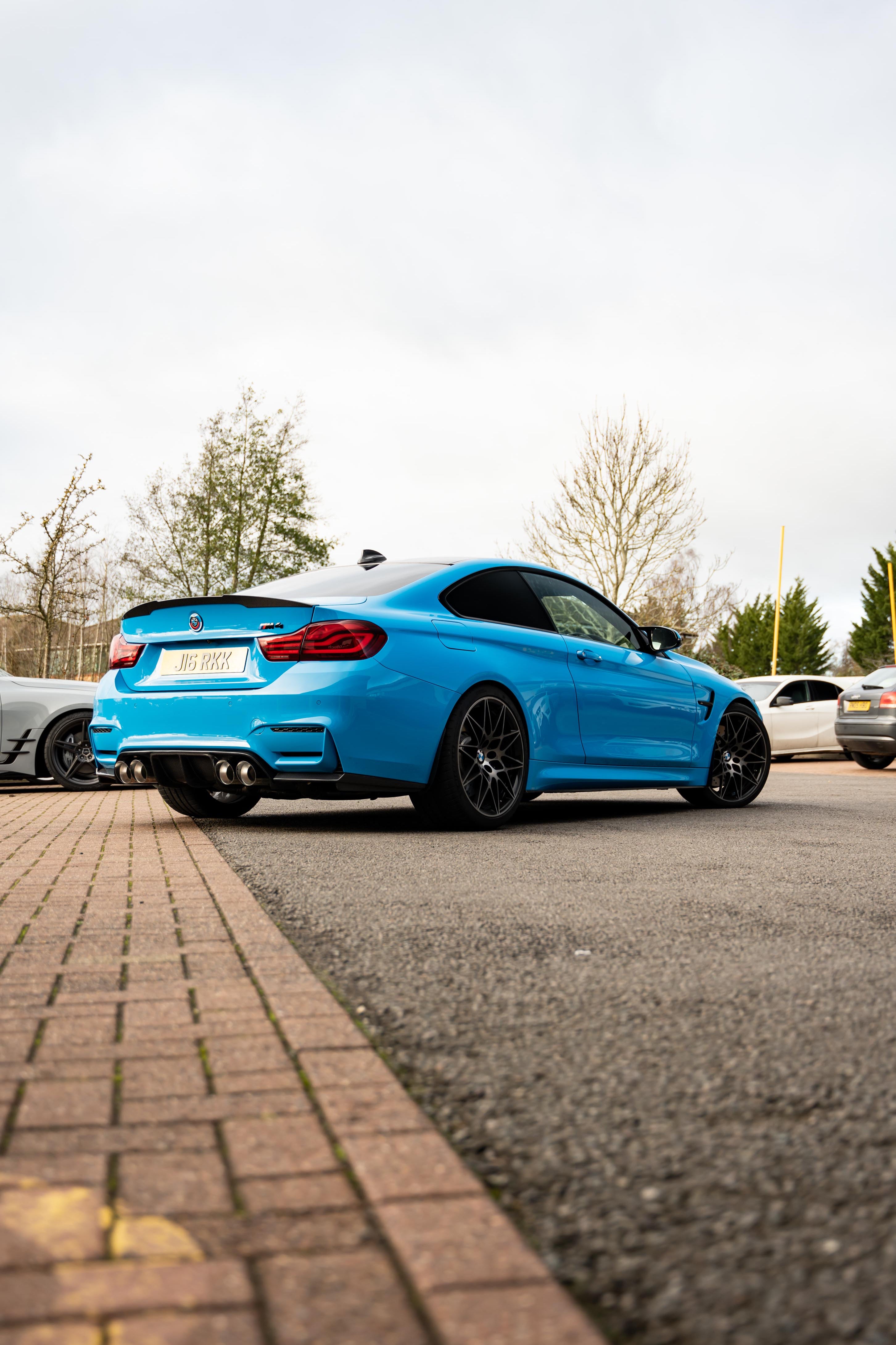 Blue BMW car on Motech Stance Springs parked on a street with trees in the background