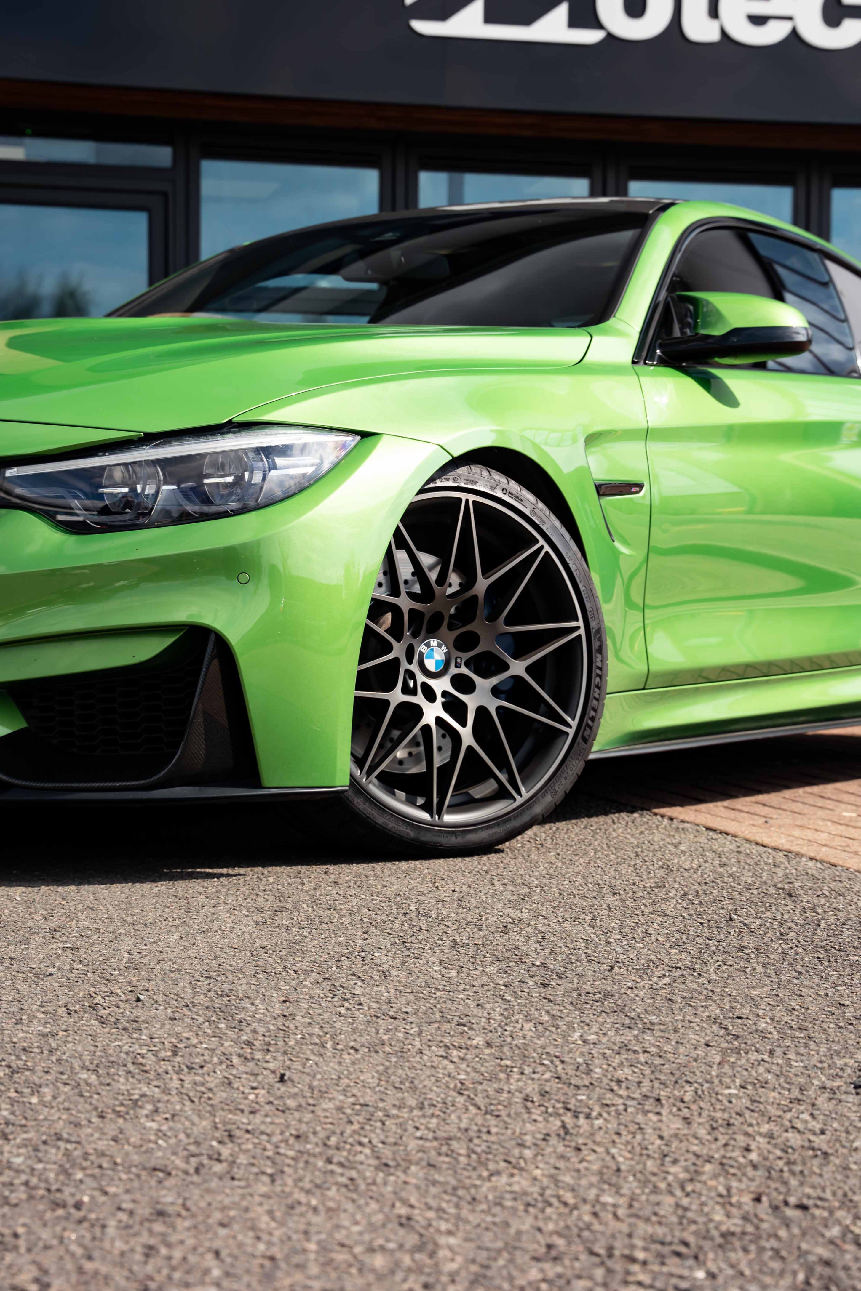 Green BMW car on Motech Stance Springs parked in front of a Motech sign