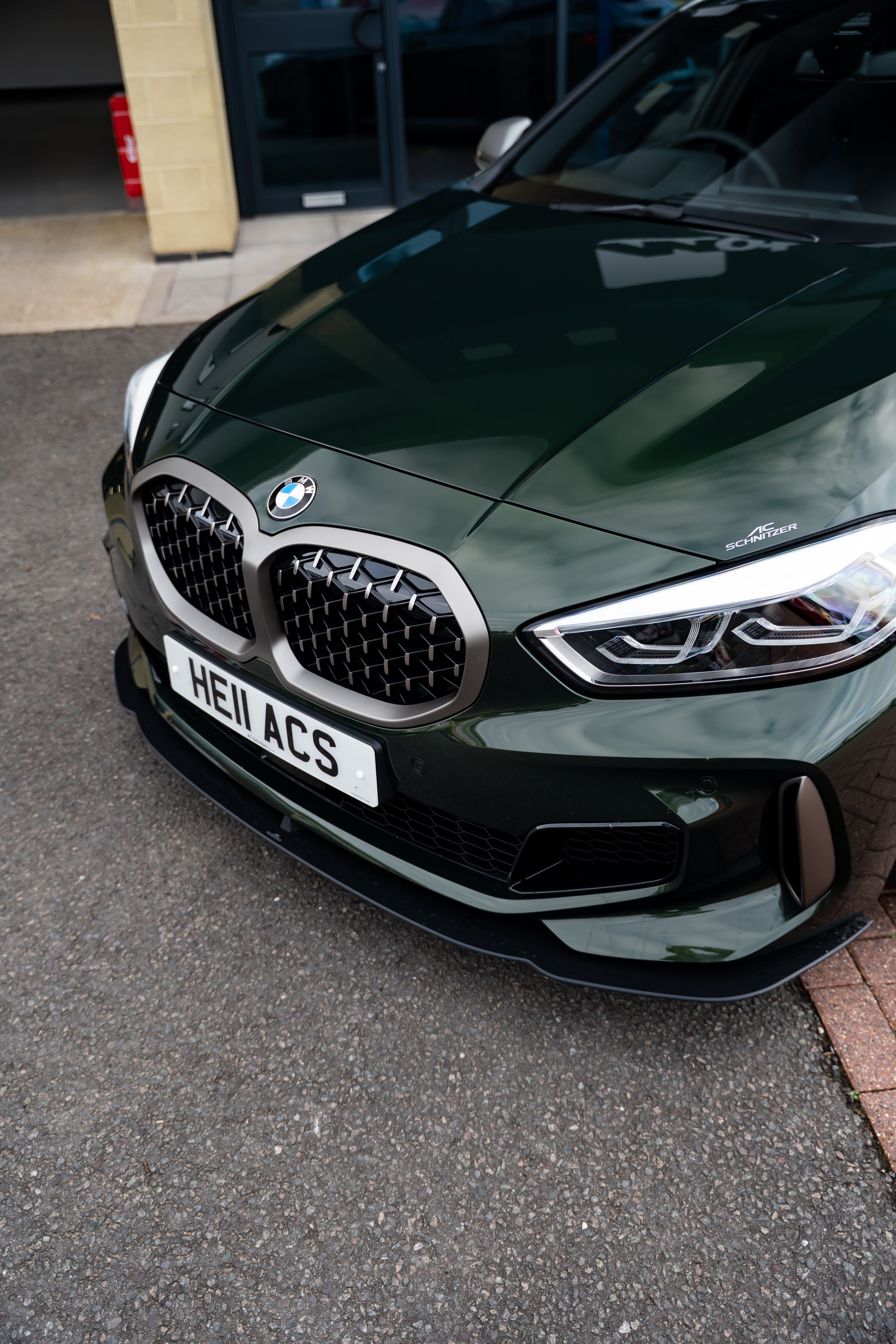 Green BMW car with an AC Schnitzer Front Splitter on a street.