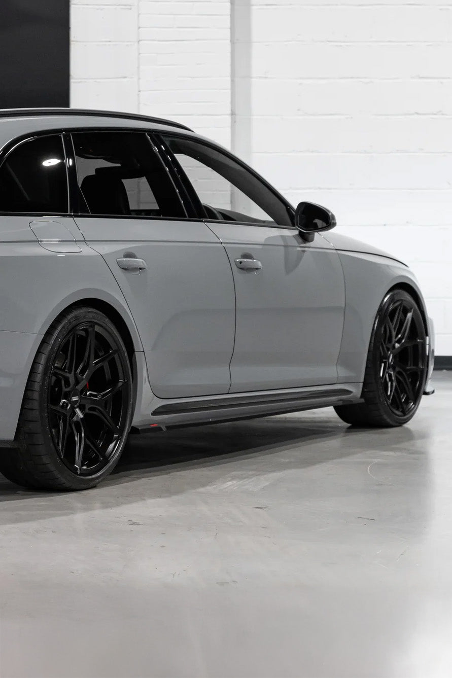 Grey car with black rims on a white floor and white wall background
