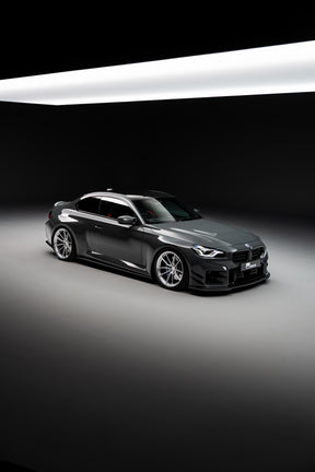 BMW M2 G87 with aftermarket wheels and lowered on springs in a high-quality photography studio. 