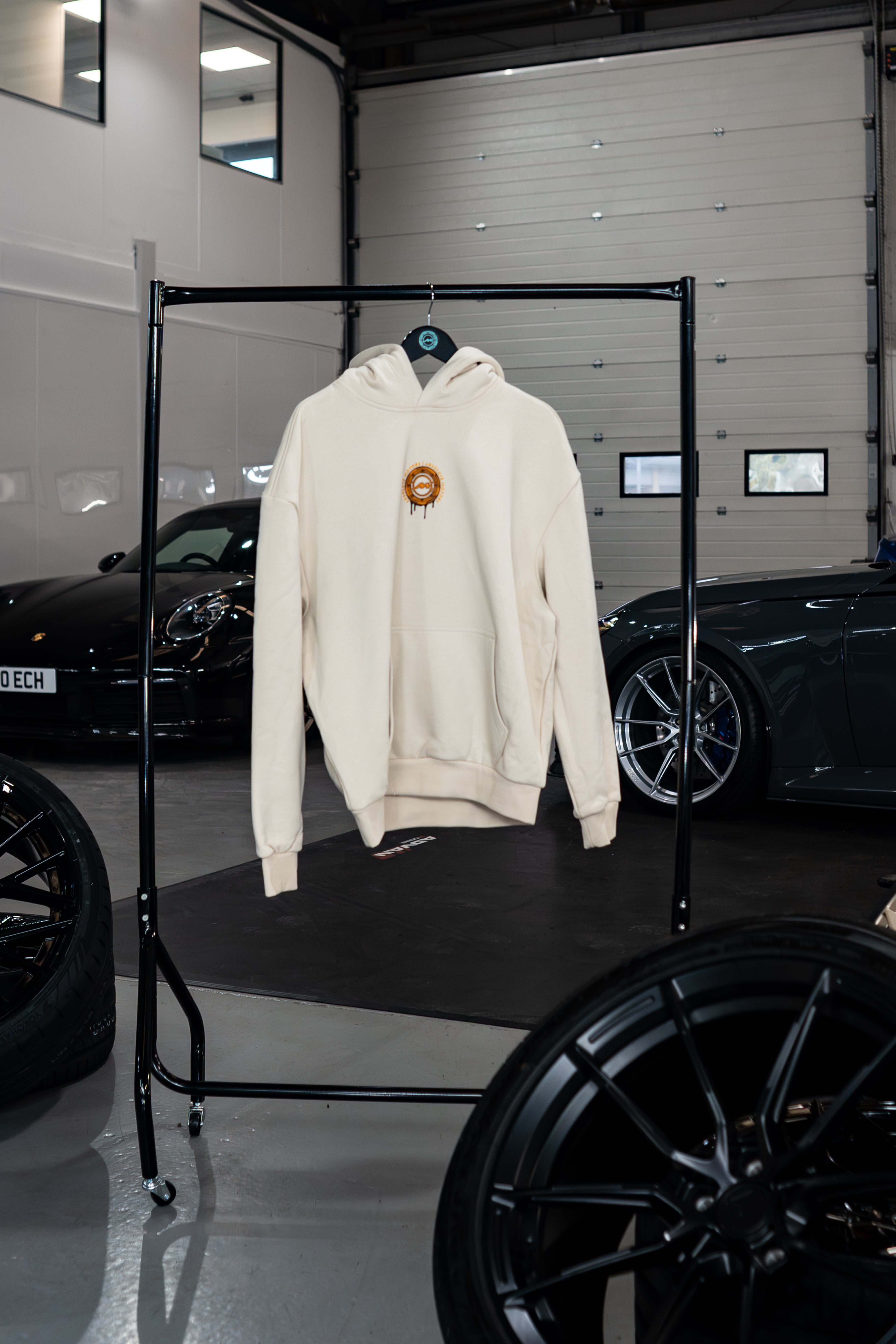Vantage Collection Sandstorm hoodie on a rack in a garage with cars in the background
