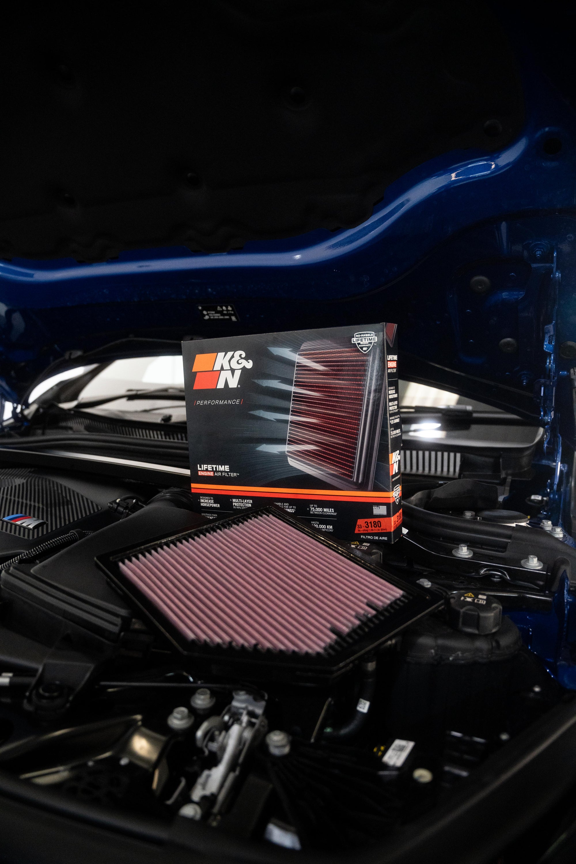 K&N air filter packaging next to a K&N air filter in a BMW engine bay.