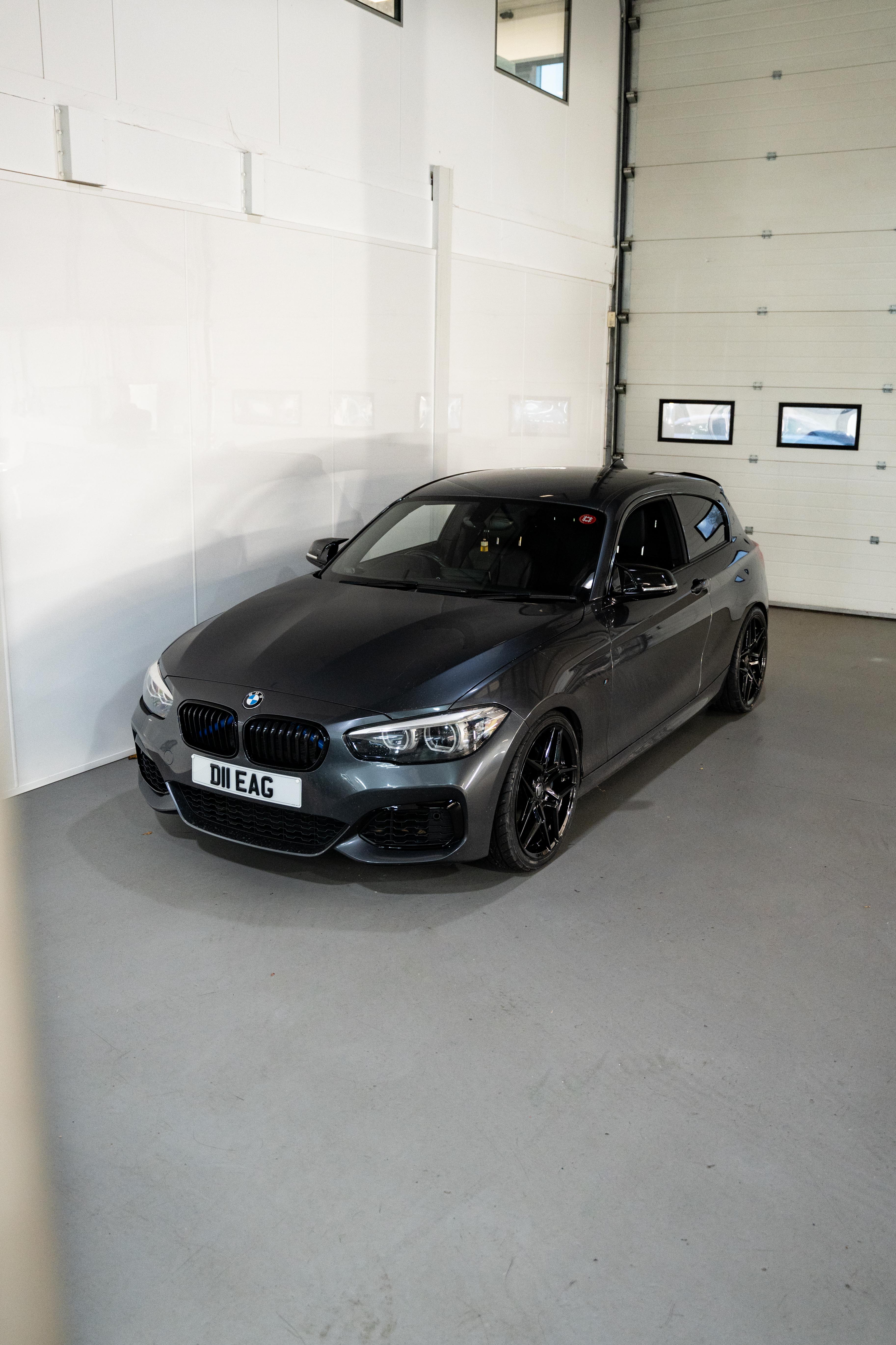 Grey BMW with Precision Black M-W1 wheels in a workshop.