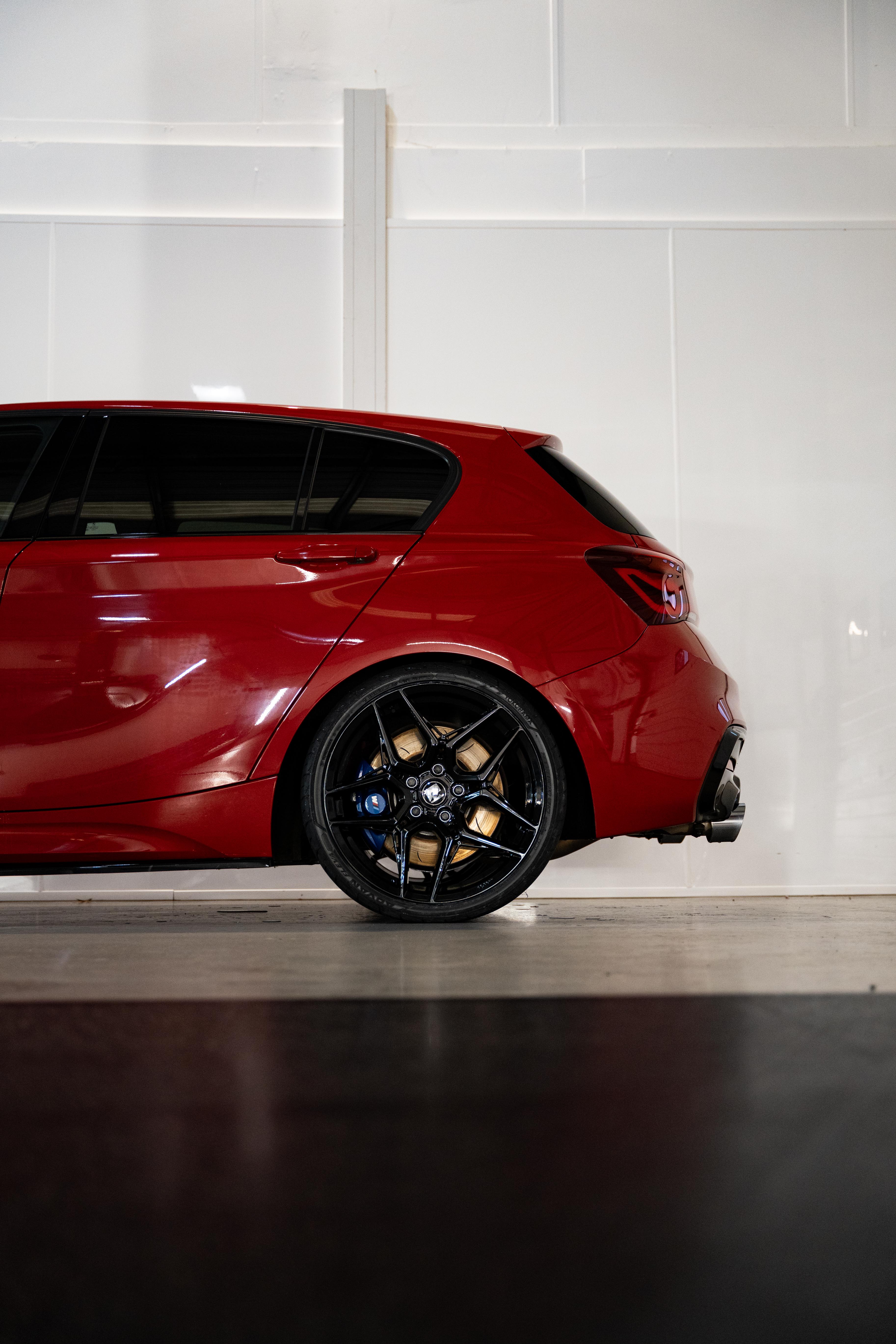 Rear shot of a red BMW with Precision Black M-W1 Wheels in a workshop.