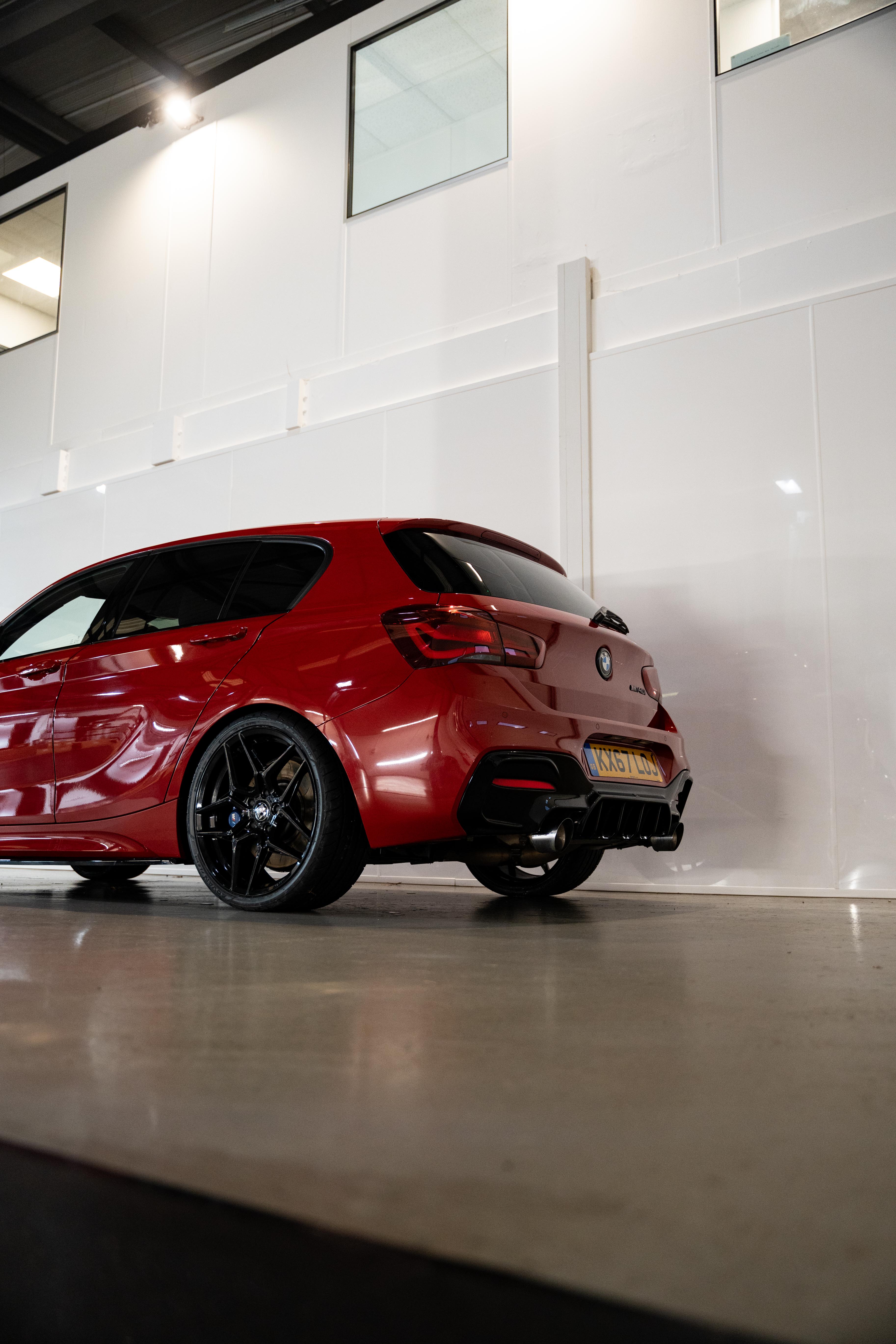 Rear shot of a red BMW with Precision Black M-W1 Wheels in a workshop.