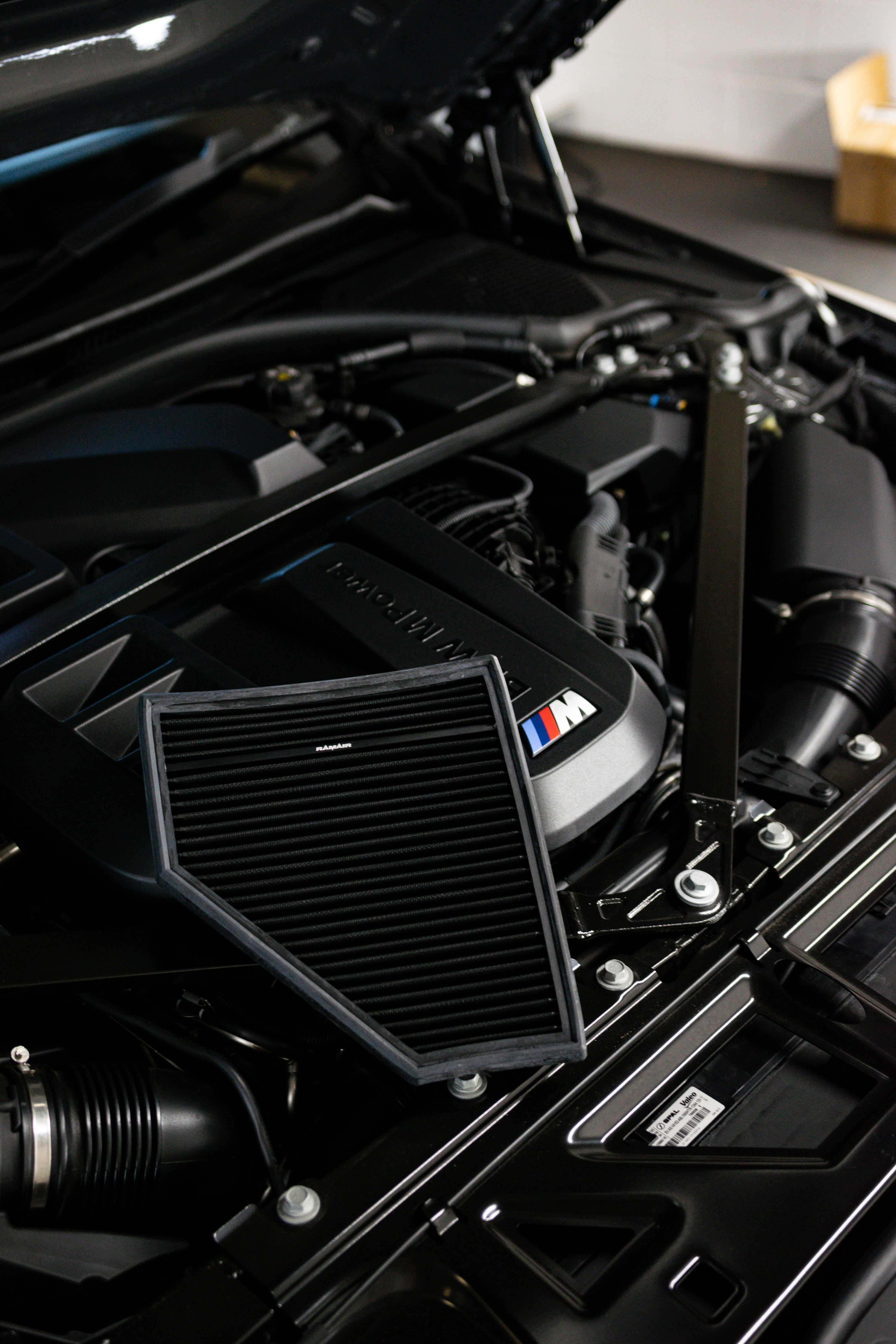 Close-up of a car engine with a prominent BMW logo and Ramair Air Filter.