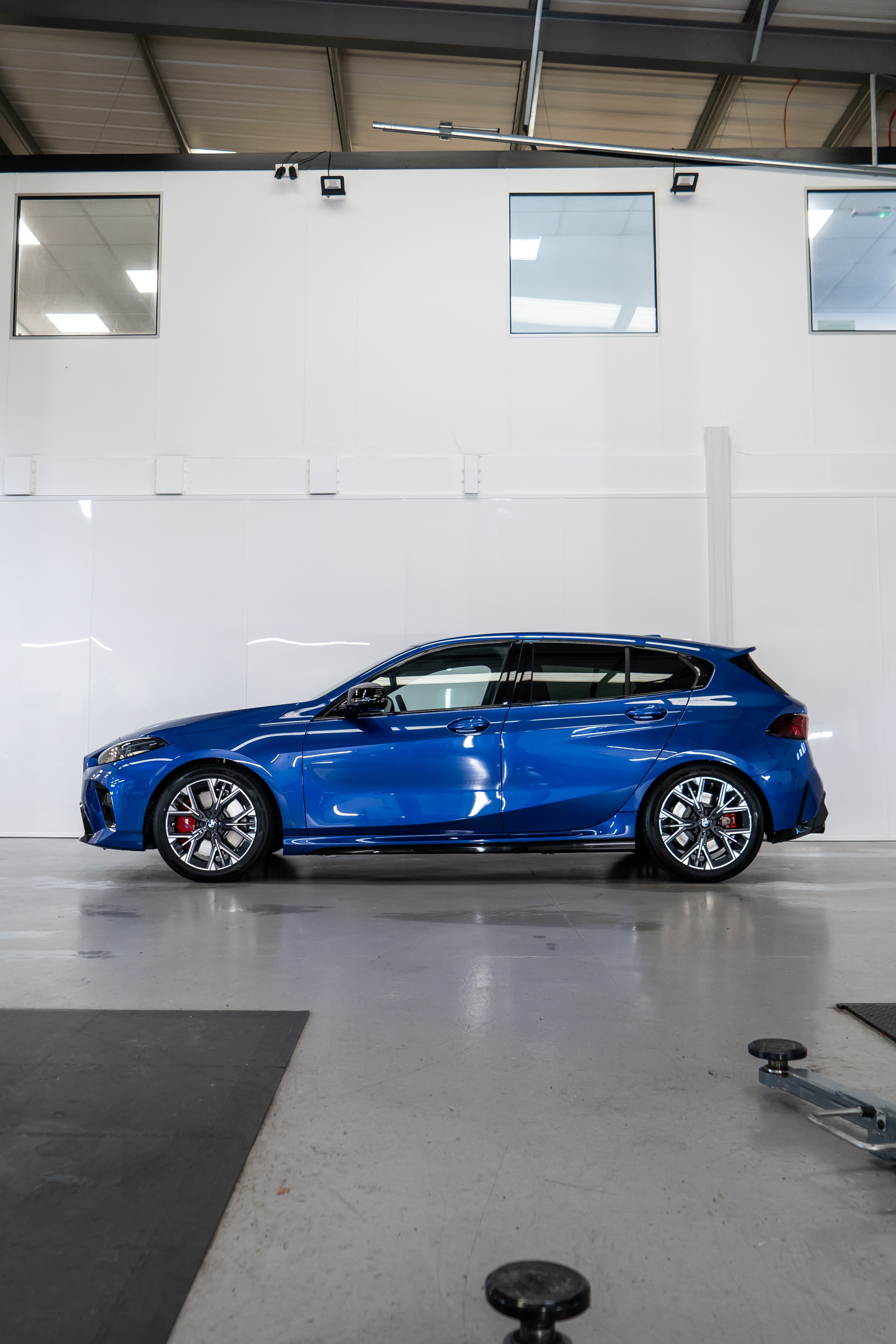 Side-on shot of a Blue BMW F70 with Motech stance springs parked in a workshop.