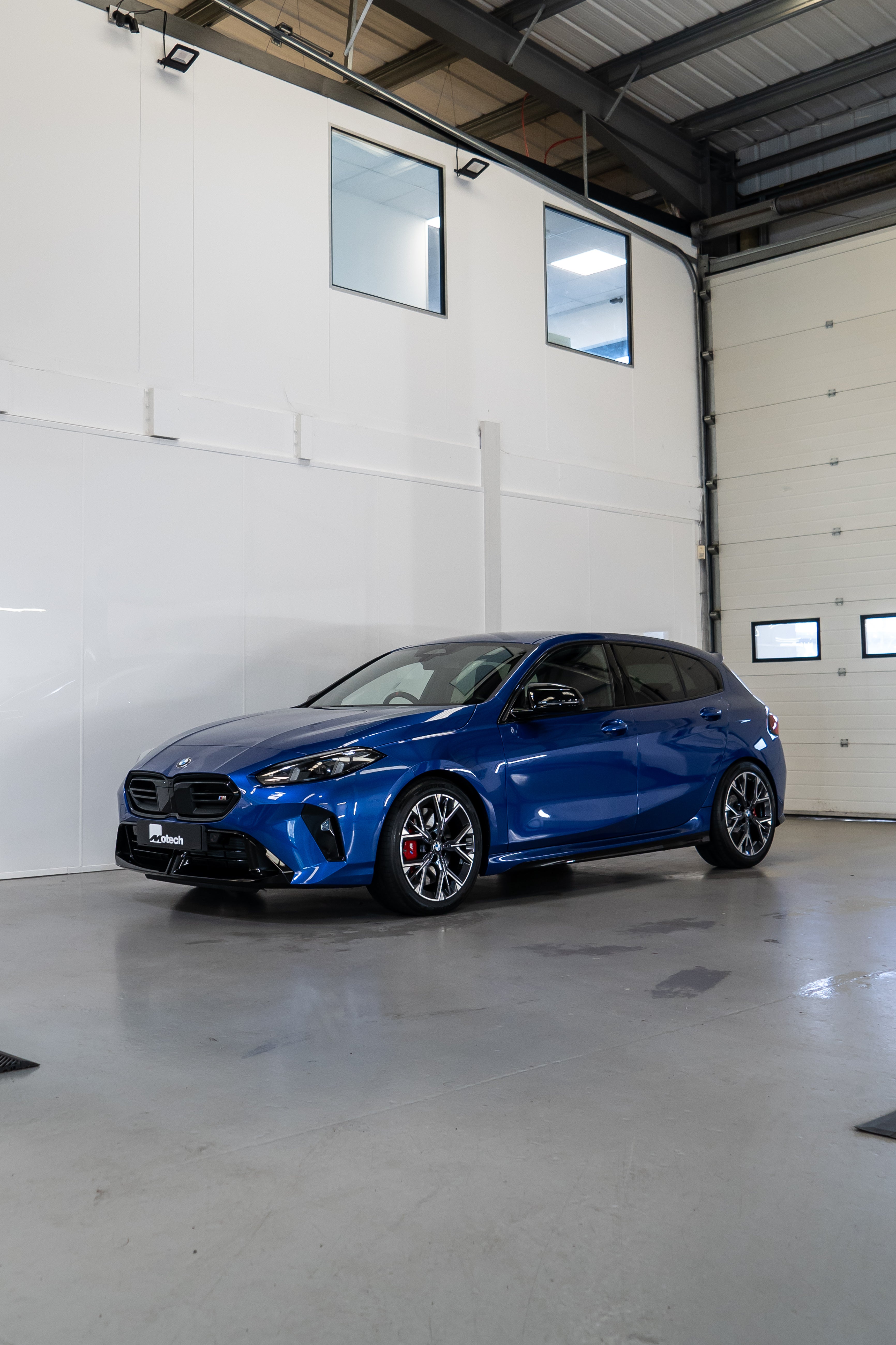 a Blue BMW F70 with Motech stance springs parked in a workshop.