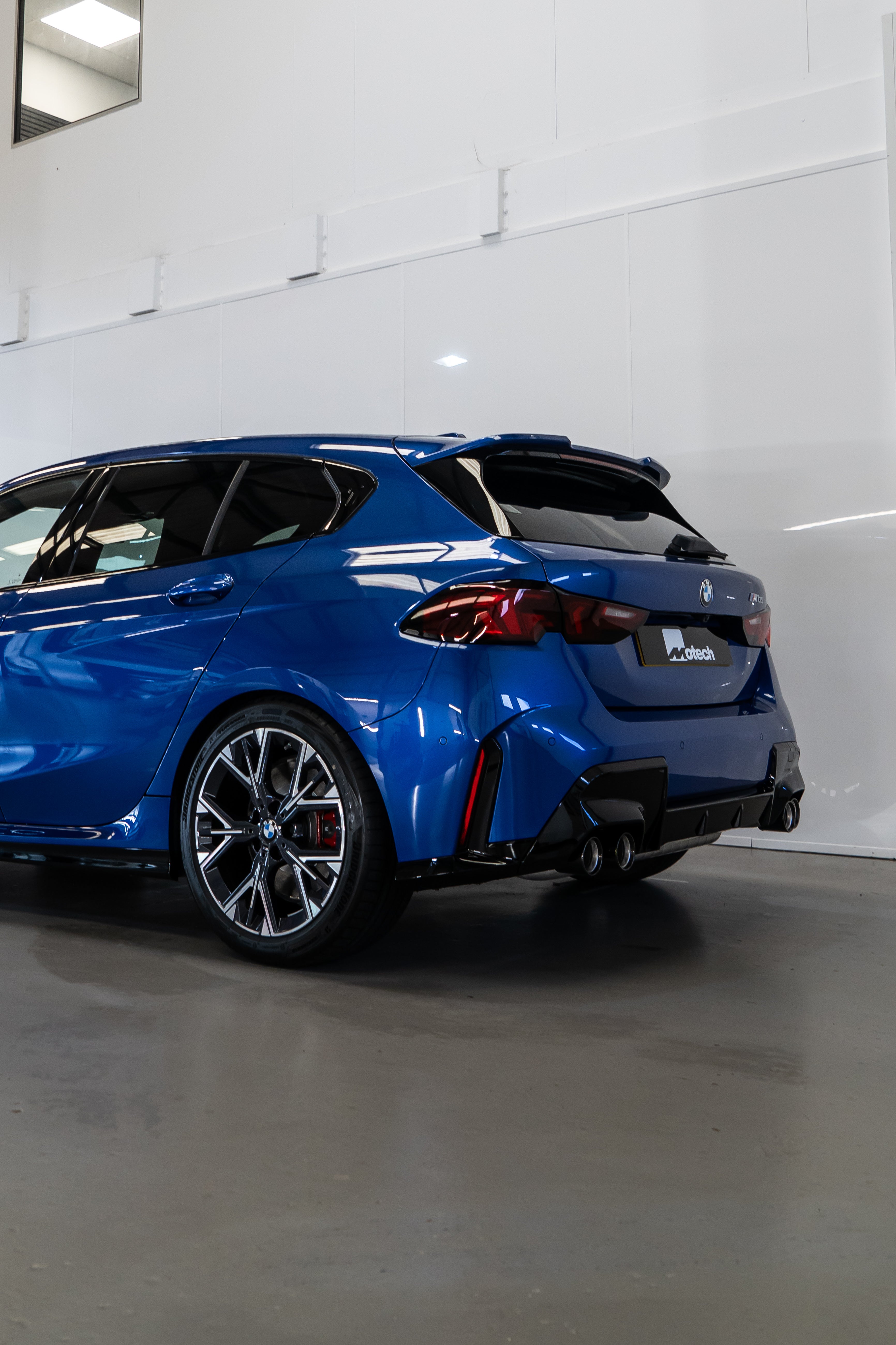 Back of a Blue BMW F70 with Motech stance springs parked in a workshop.